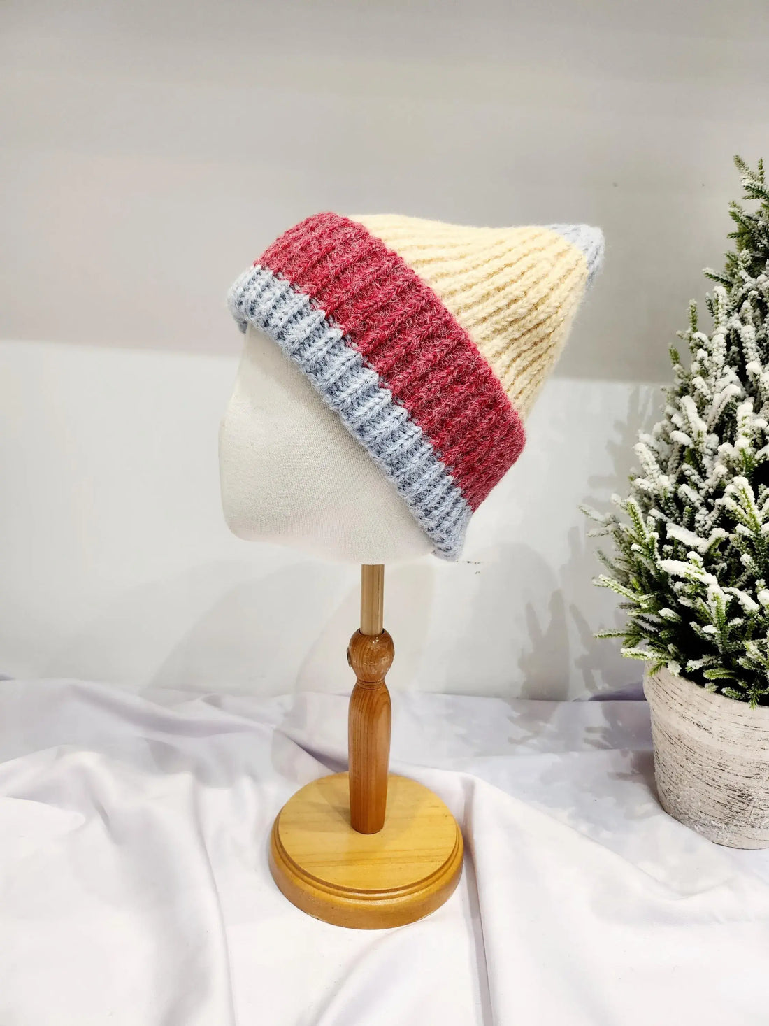 anna angora beanie: Cream, red, and blue striped knitted beanie displayed on a mannequin head. Soft angora blend for warmth and style.