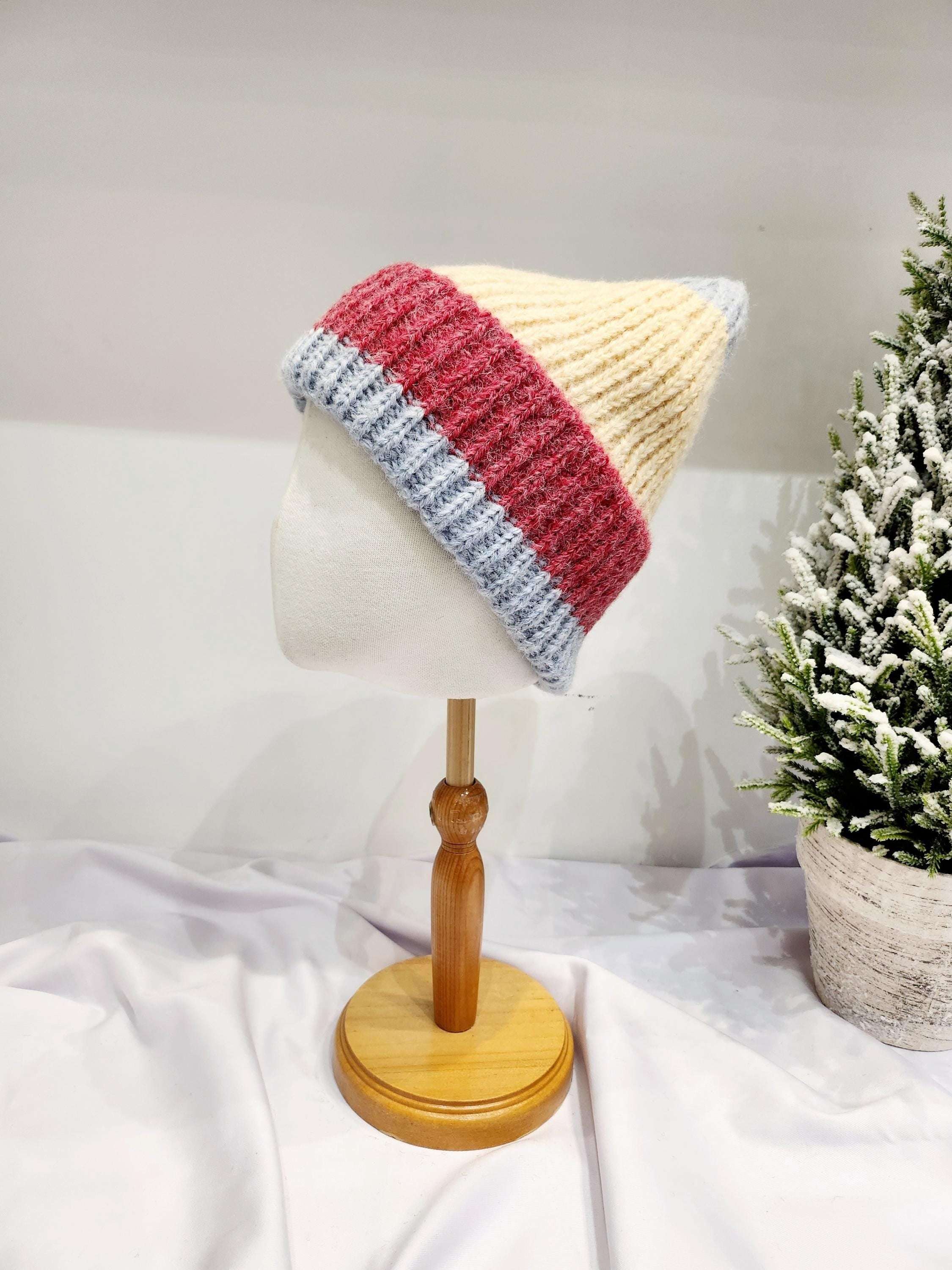anna angora beanie: a cozy, hand-knit hat with cream, red, and gray stripes, displayed on a mannequin head. Soft angora blend.