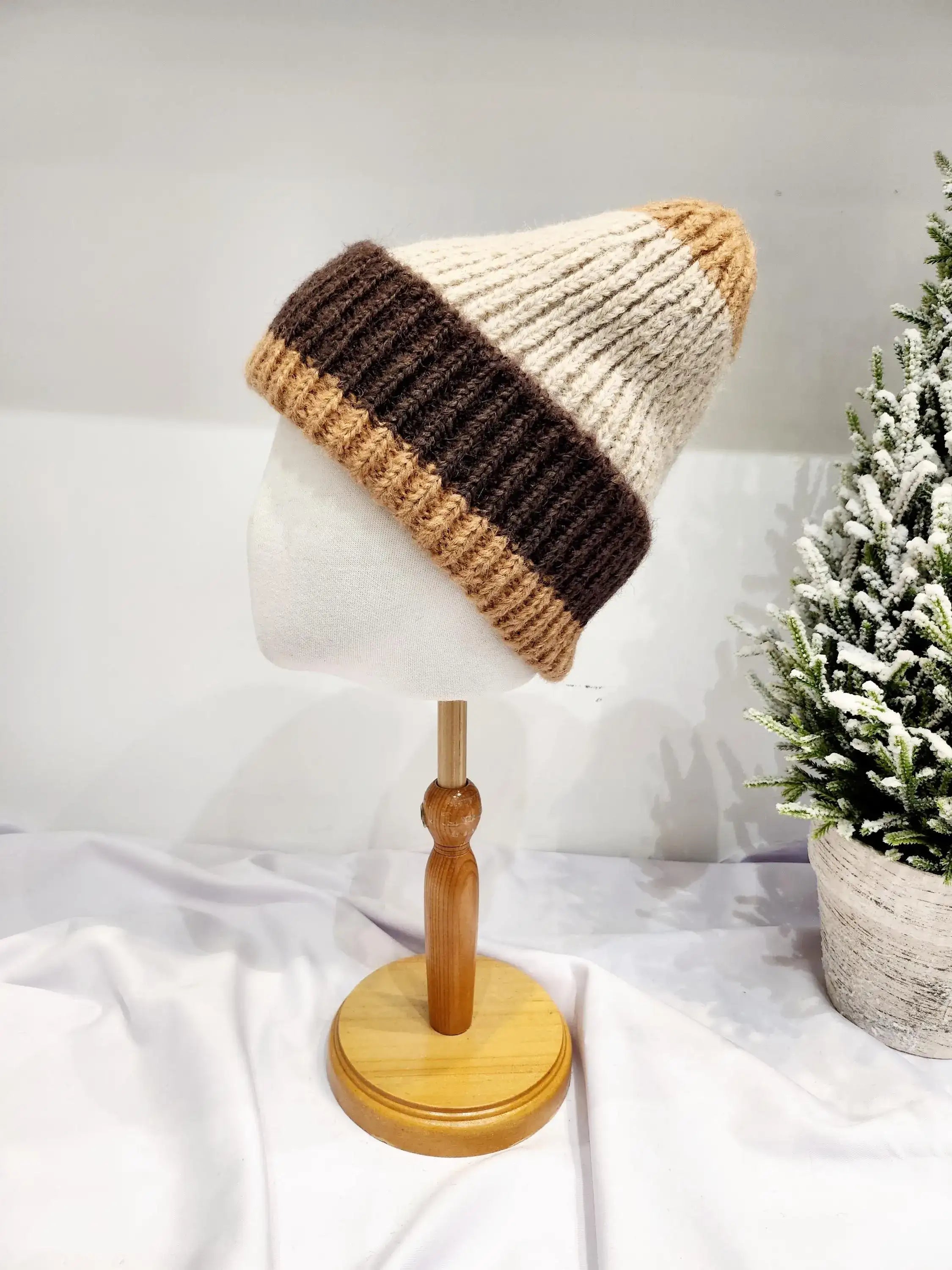 anna angora beanie: Brown and beige knitted hat on a mannequin head. Features color block design and cozy texture.