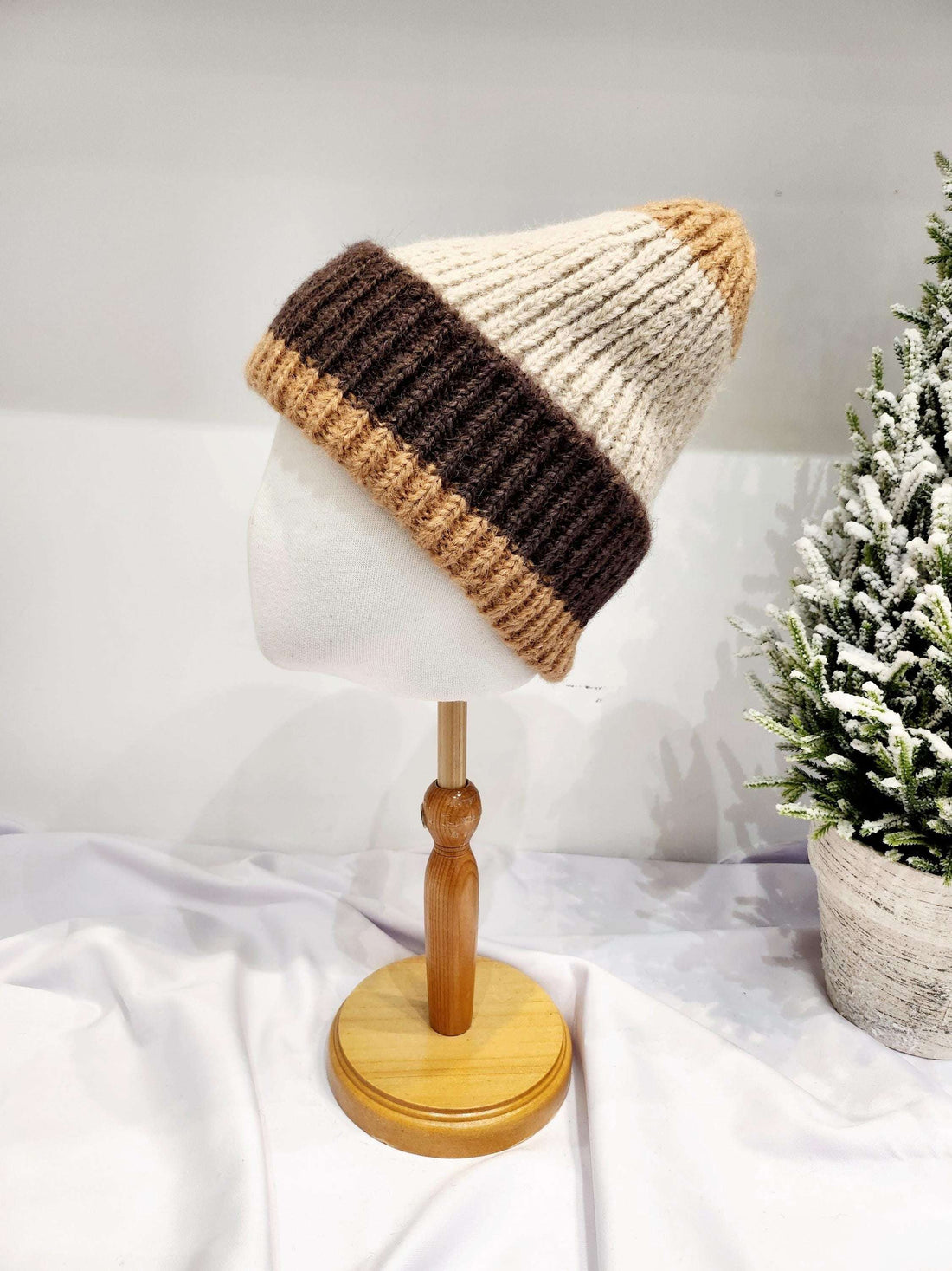anna angora beanie: hand-knitted hat with dark brown and beige color blocks, displayed on a mannequin head. Warm and stylish for winter.