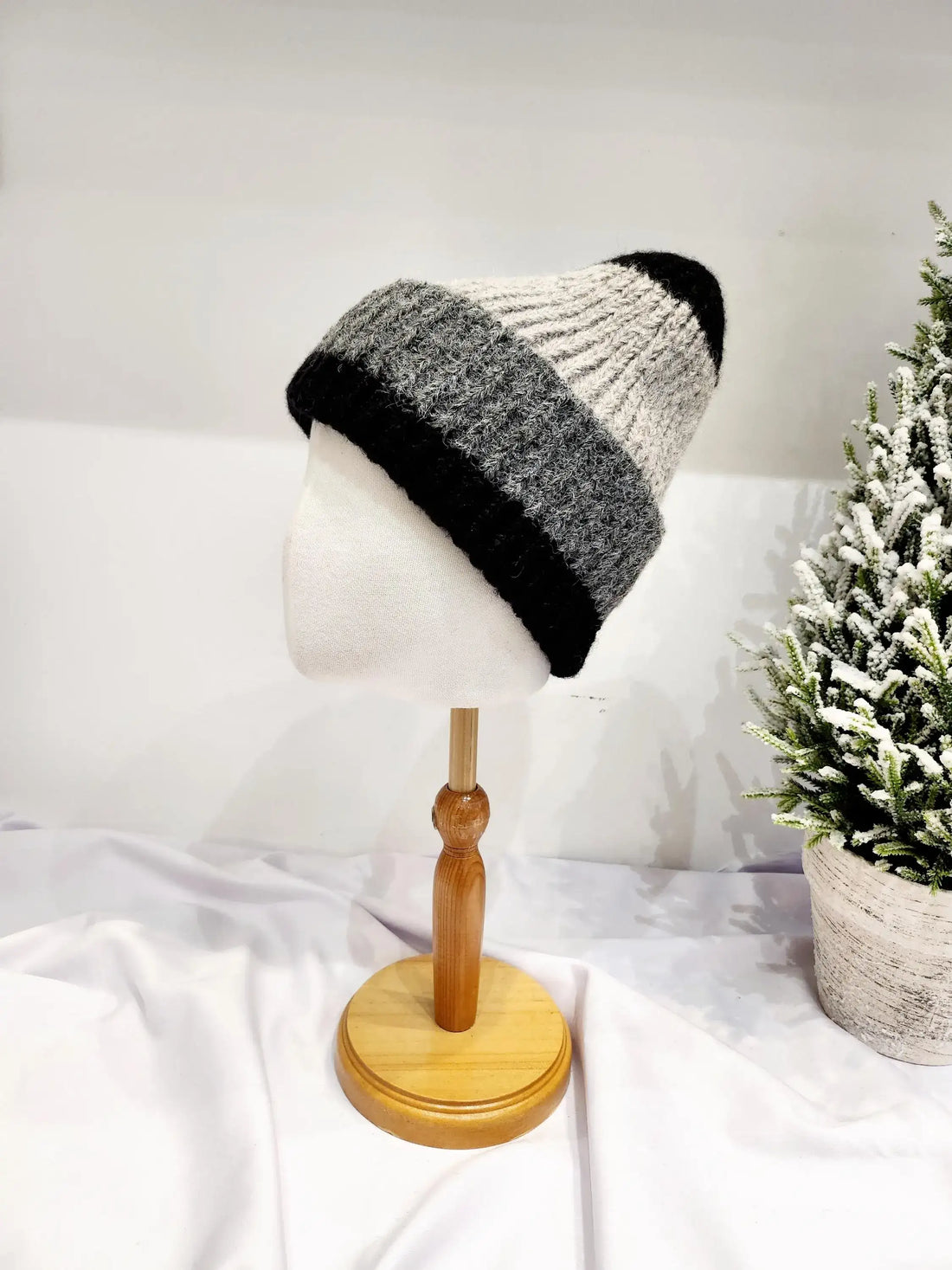 anna angora beanie: a cozy, striped wool hat in black, grey, and off-white, displayed on a mannequin head.