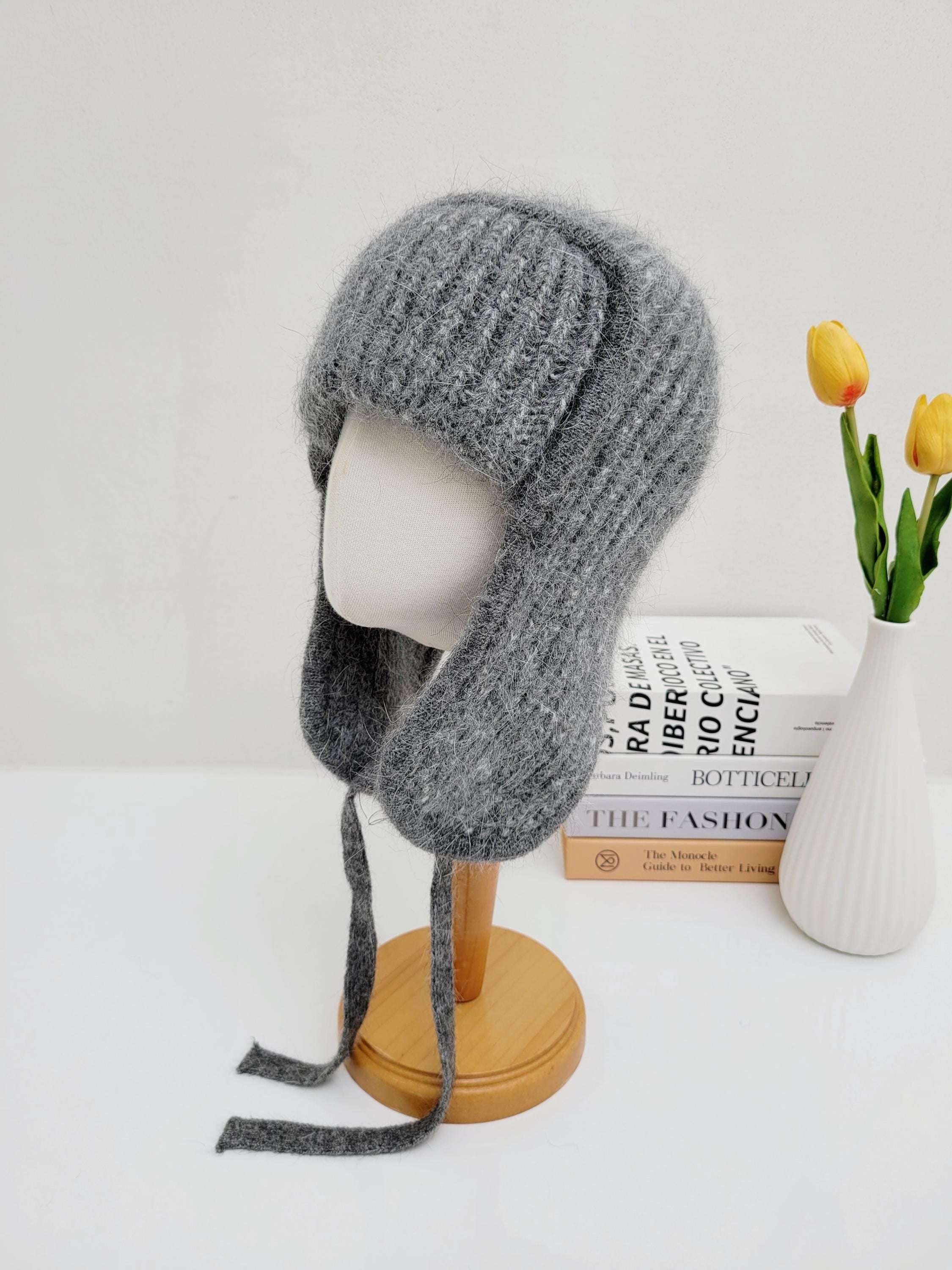 West mountain angora trapper hat in heather grey knit. Features ear flaps with dangling ties. Shown on a mannequin.