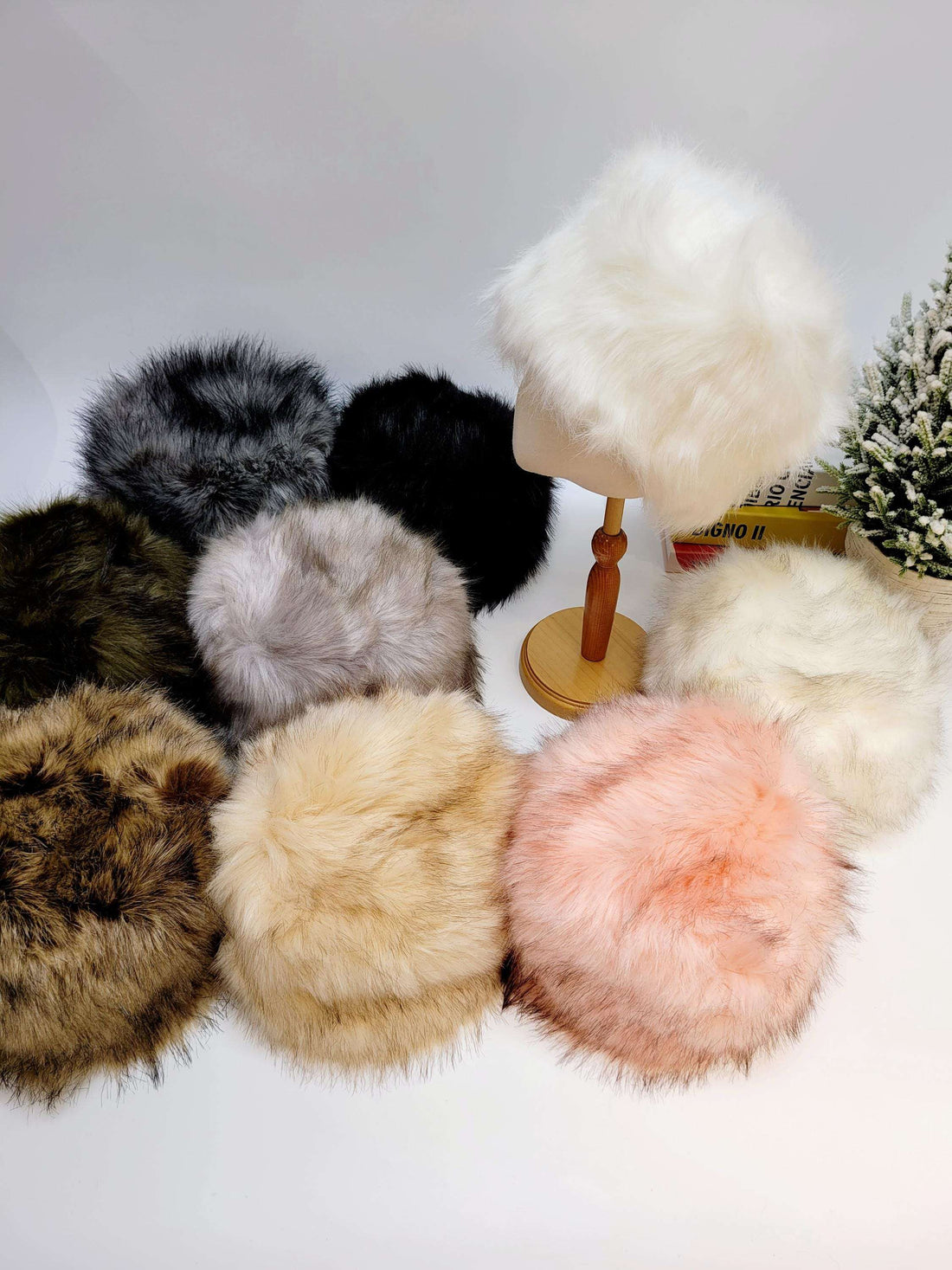 sonya hat fluffy collection: plush faux fur hats in white, black, gray, brown, beige, green, and pink. One is displayed on a wooden stand.