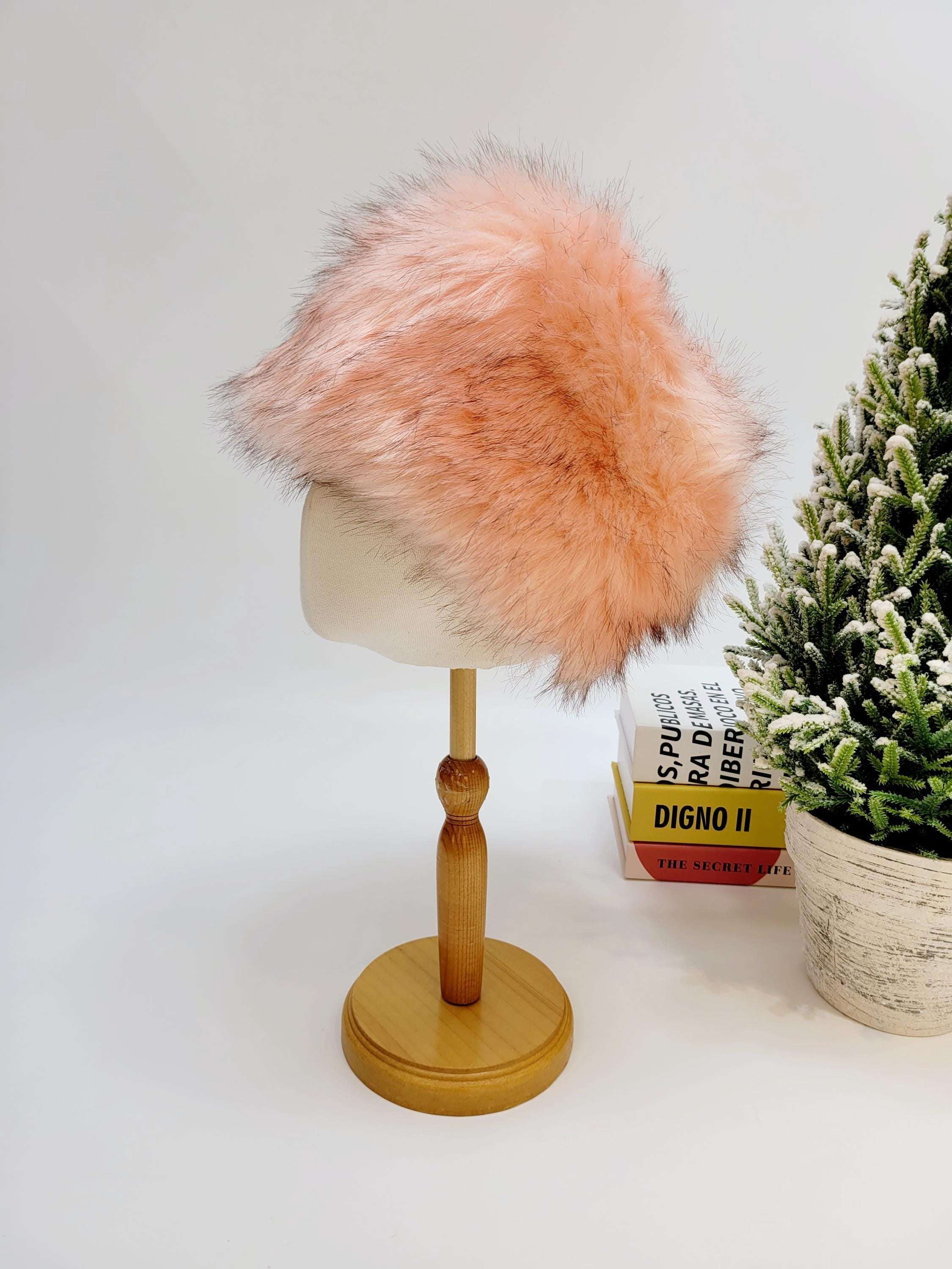 Pink sonya hat fluffy made of soft faux fur, displayed on a wooden stand.