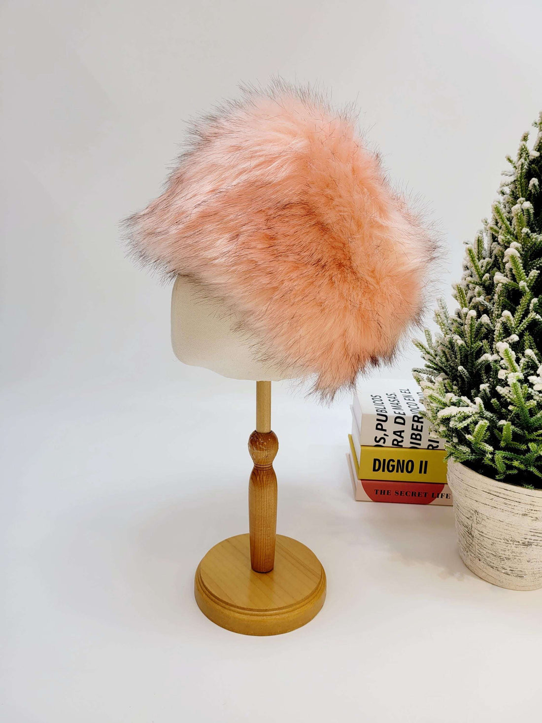 Pink sonya hat fluffy made of soft faux fur, displayed on a wooden stand.