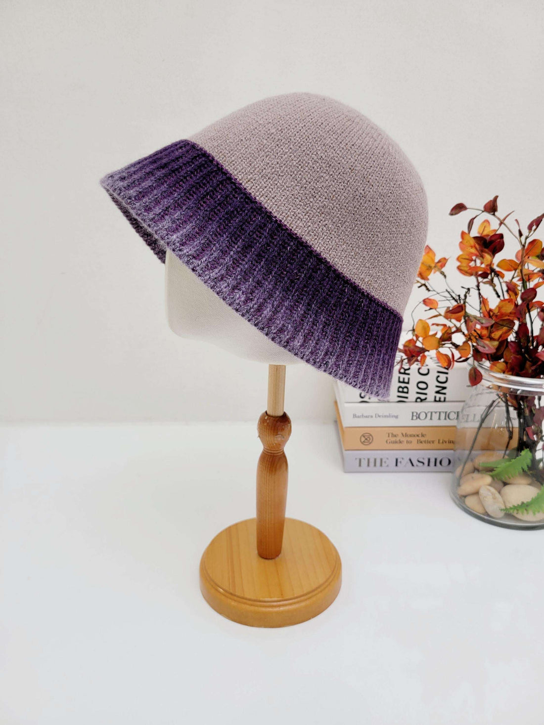 Two-tone knitted diana hat: heathered light purple crown meets a darker purple brim, displayed on a wooden stand.