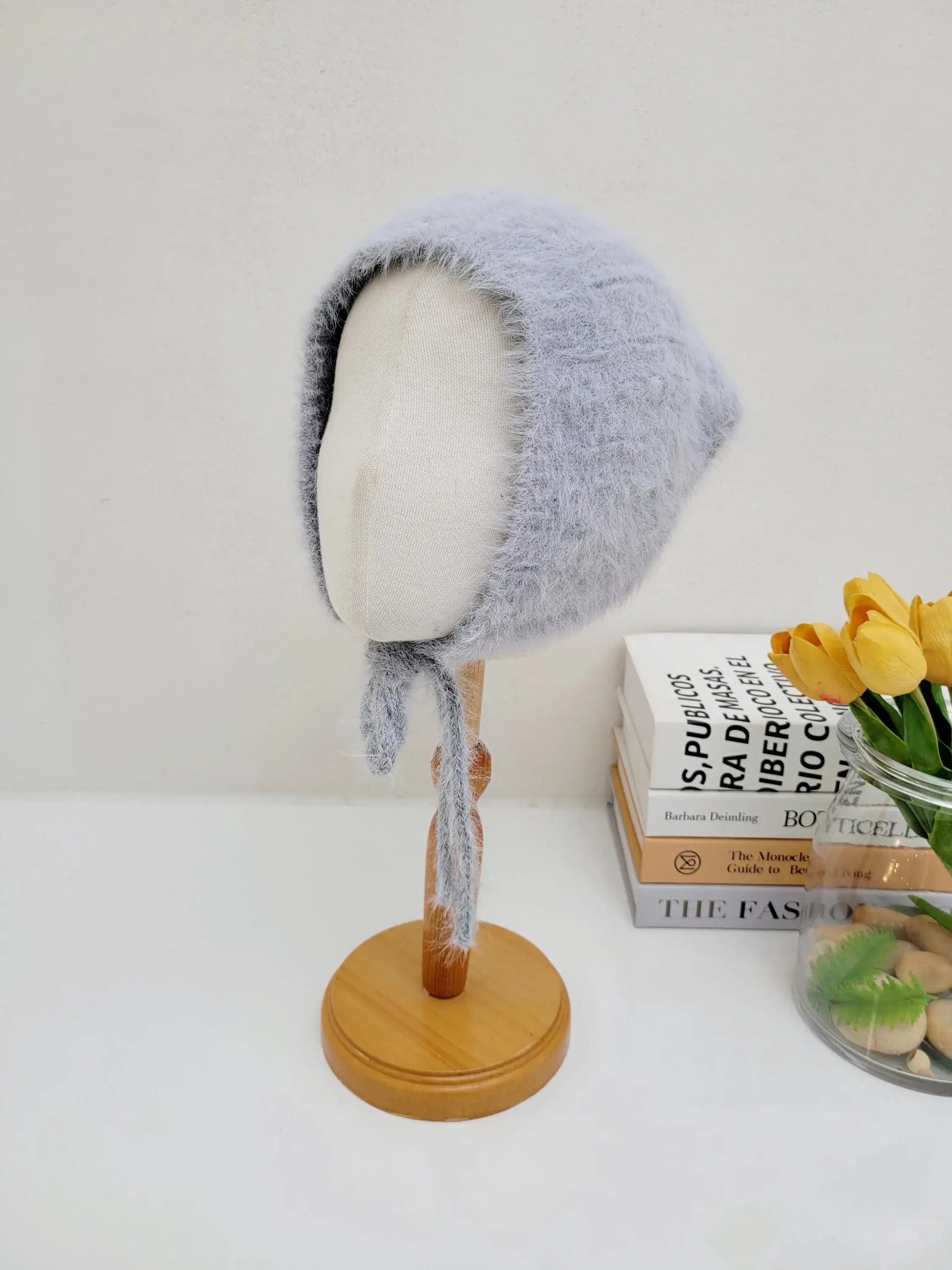 Light blue furry "little riding hood" bonnet with tie strings, displayed on a mannequin head.