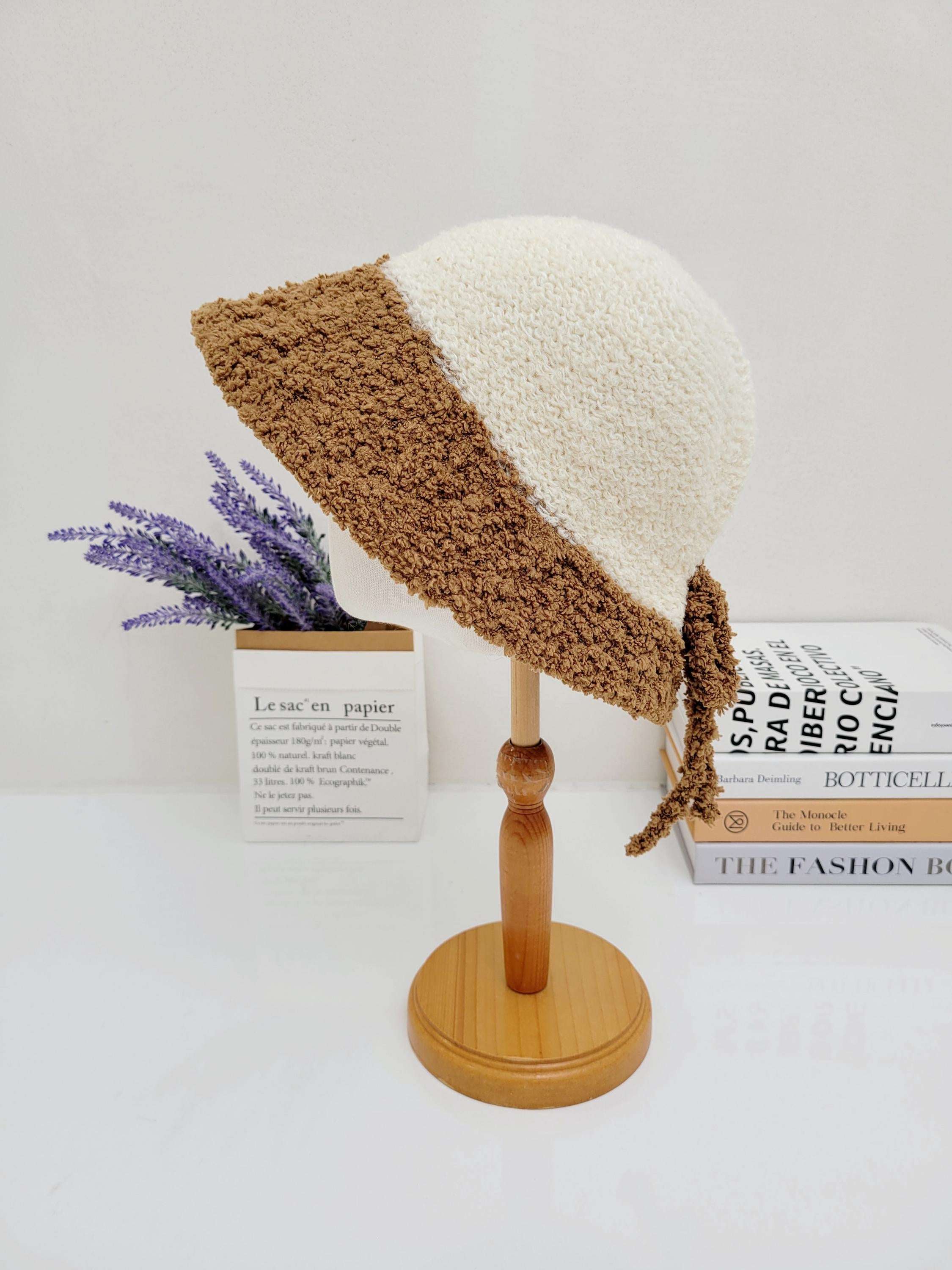 Cream and brown boho bucket - sherpa hat on a wooden stand with fuzzy texture and tie details.
