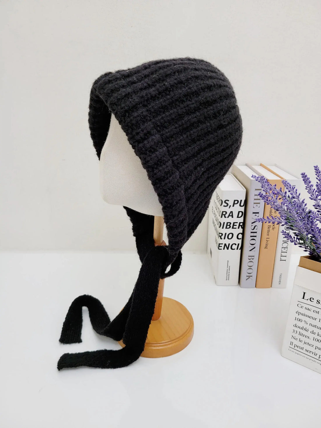 Black knit tour le jour bonnet on a mannequin, featuring a ribbed texture and long, elegant ties.