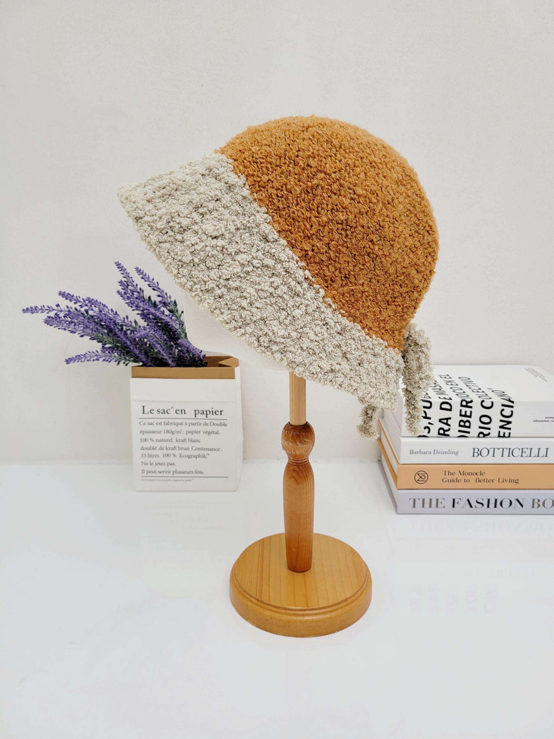 BOHO BUCKET - SHERPA: Two-tone sherpa bucket hat in brown and beige, displayed on a wooden stand.