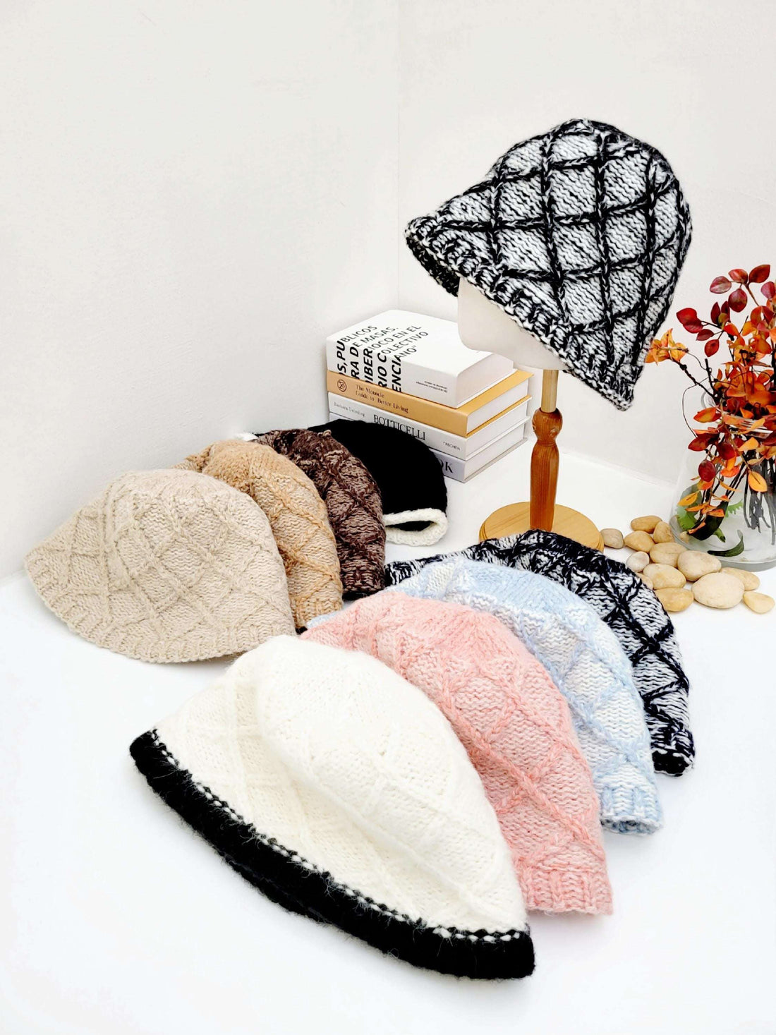Knitted bucket hats, including a black and white diamond pattern on a mannequin, plus solid beige, brown, pink, blue, and black/white trim variations.