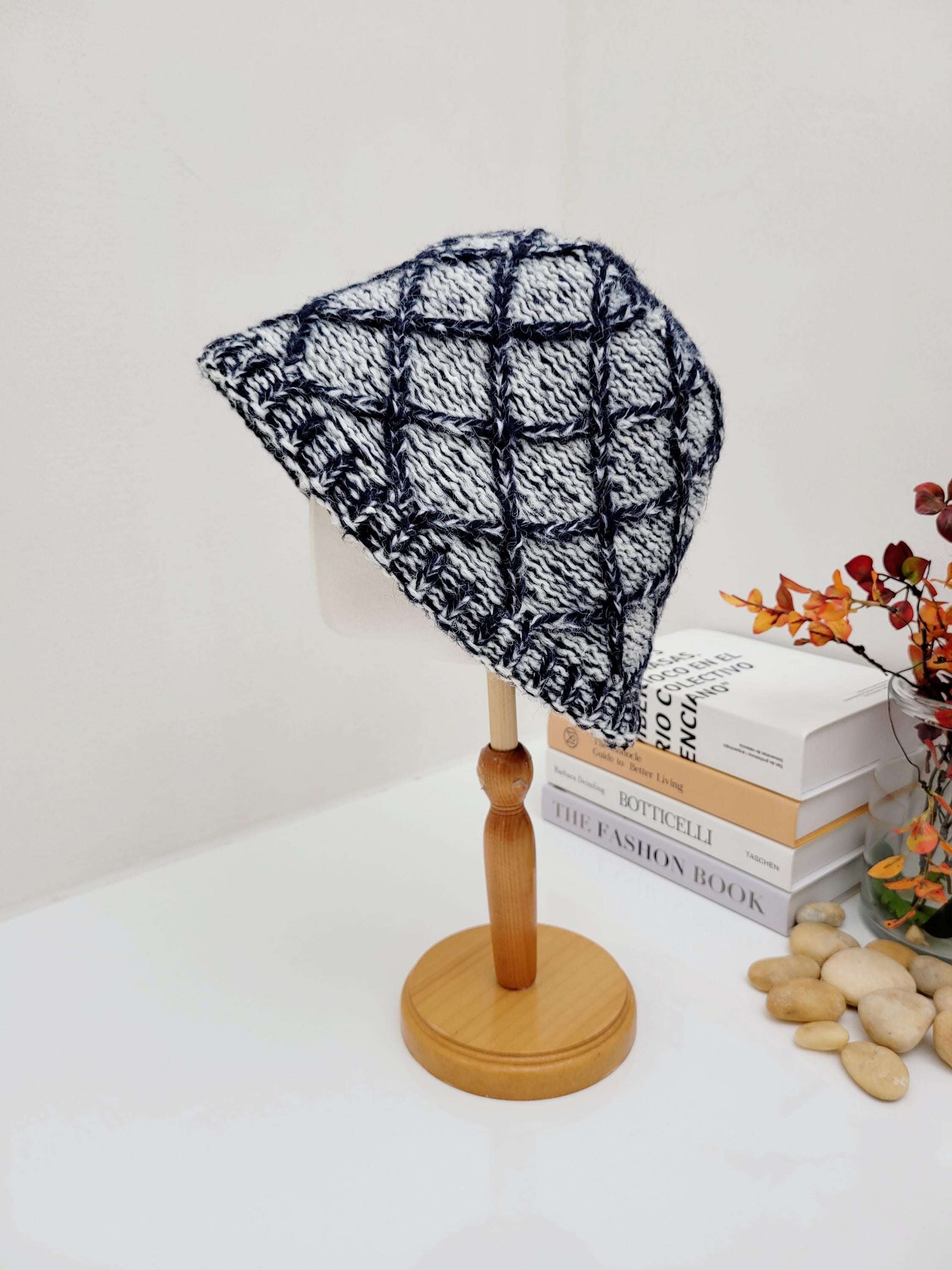winter in the paris knitted hat with a stylish black and white checkered pattern, displayed on a wooden stand