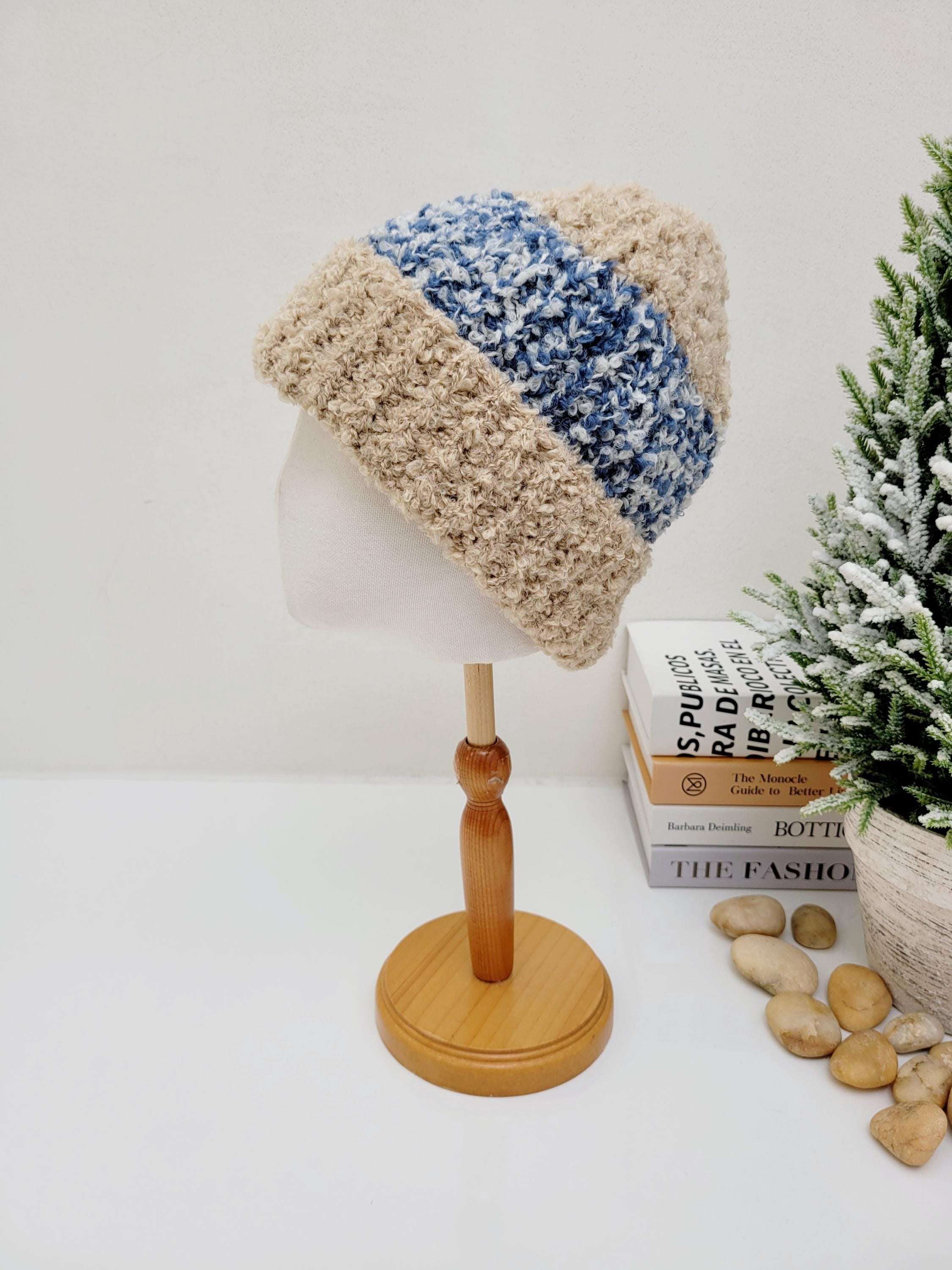 Two-tone tokyo beanie: beige and blue knitted hat on a wooden stand. Warm and stylish winter accessory.