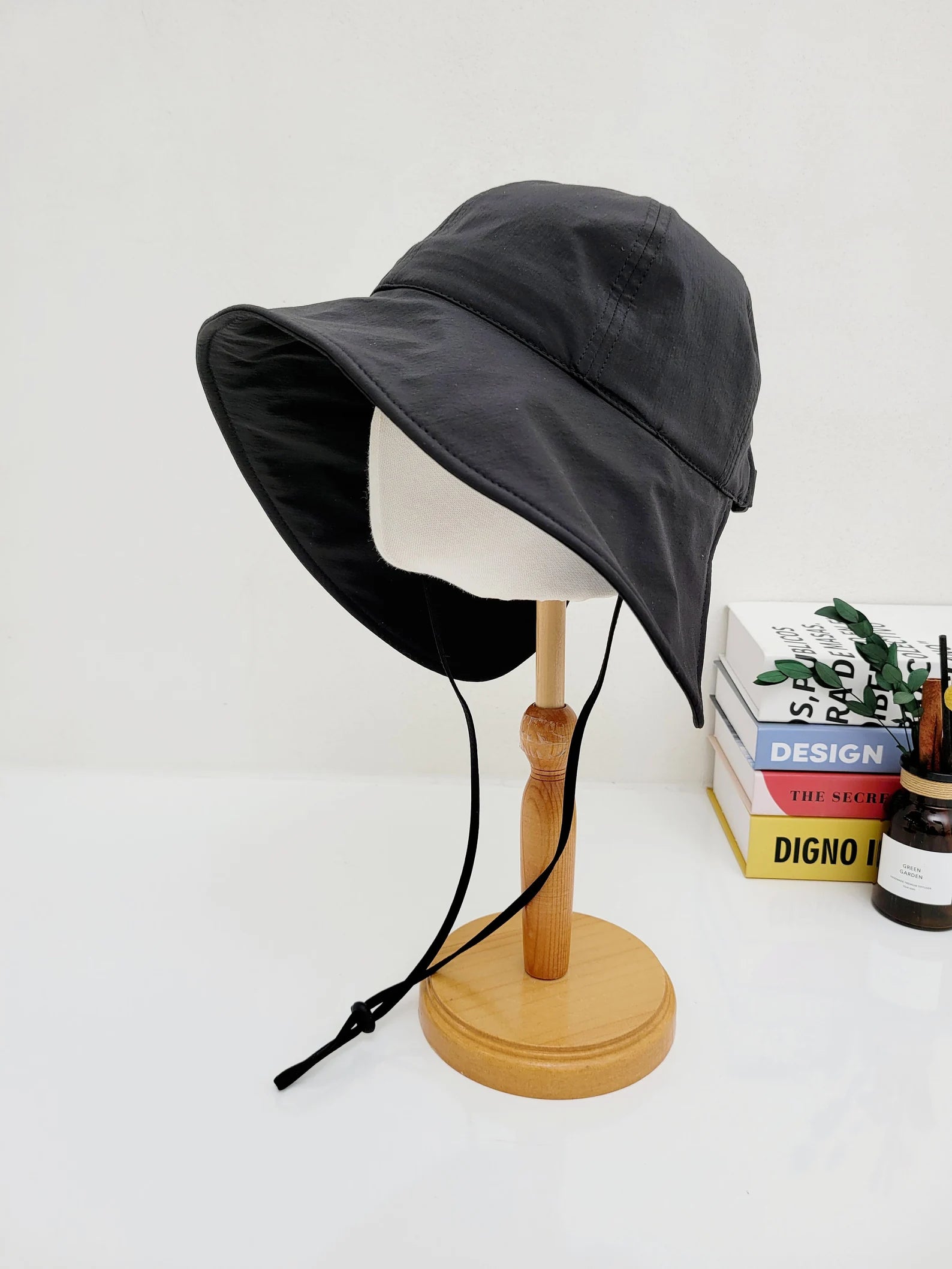 
Black summer large brim hat on a stand, with a wide brim and adjustable chin strap.
