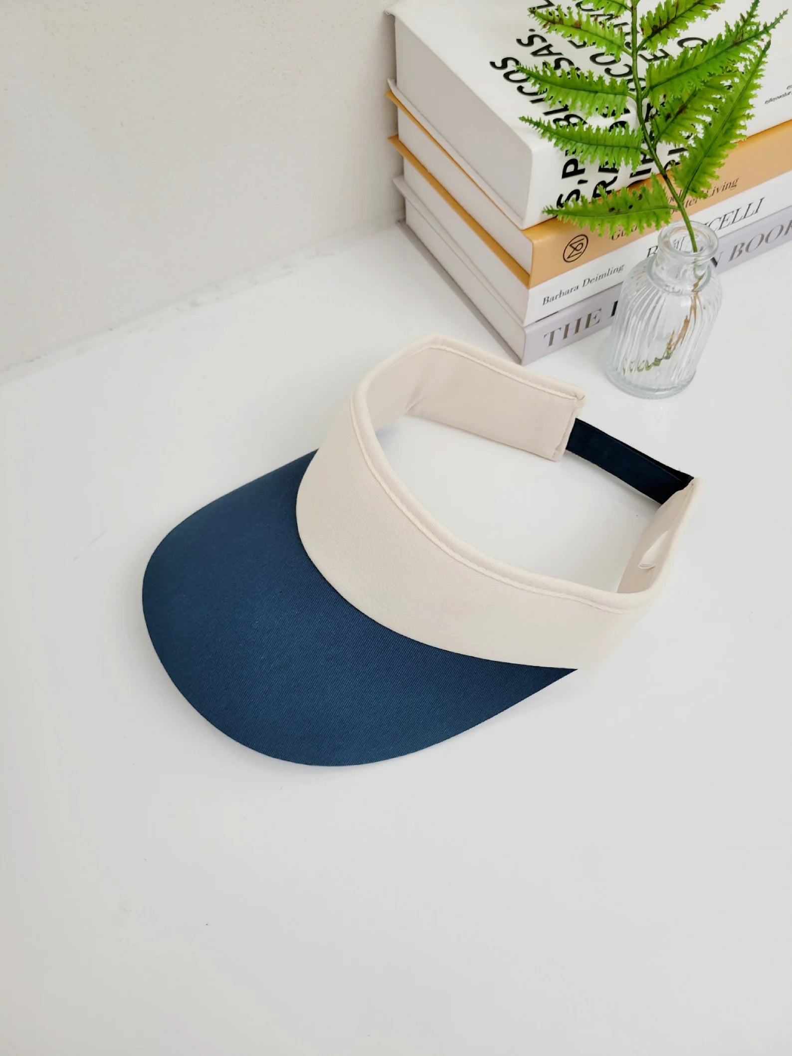 Two-tone sports sun visor: navy blue brim with a beige band and black elastic. Stylish sun protection.
