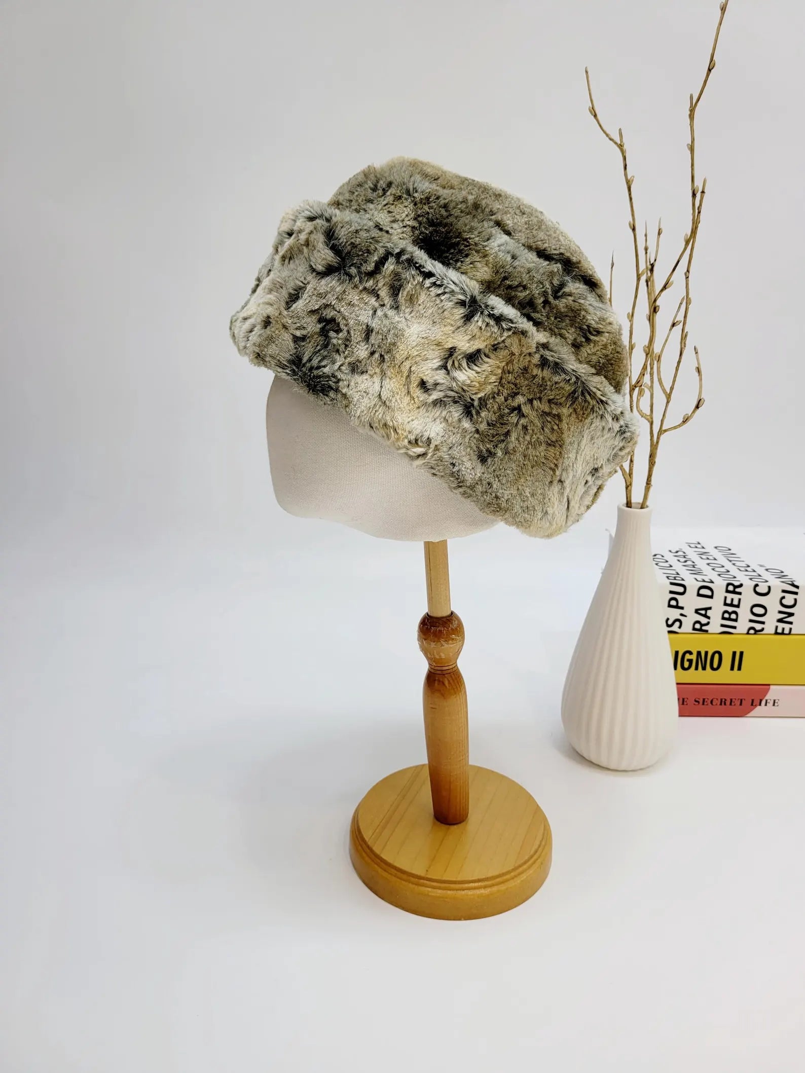 Faux fur russian hat in mottled gray and cream, displayed on a mannequin head. Soft, winter-ready style.
