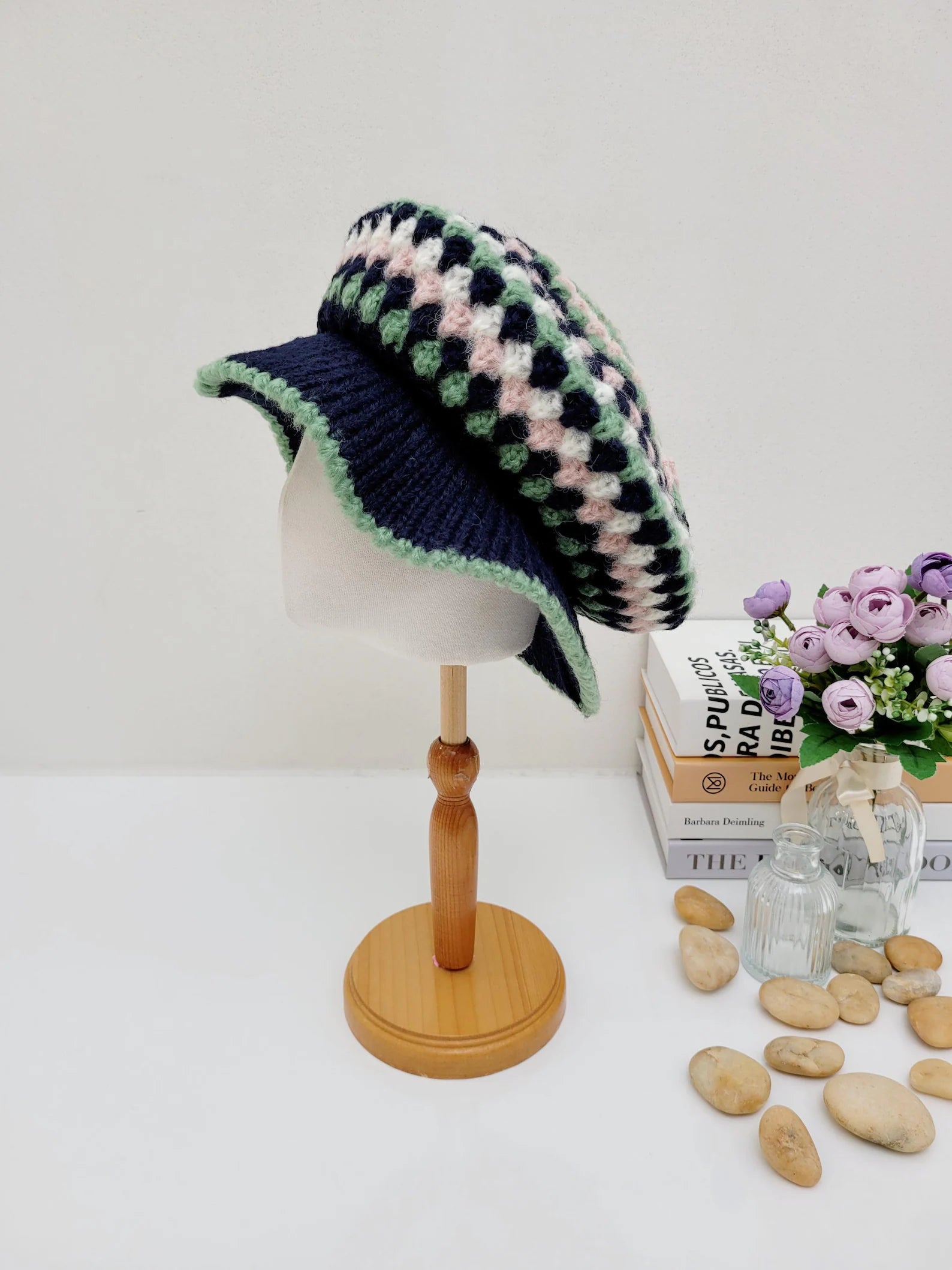 A collection of crocheted beret hats in various colors displayed on a wooden stand and table.