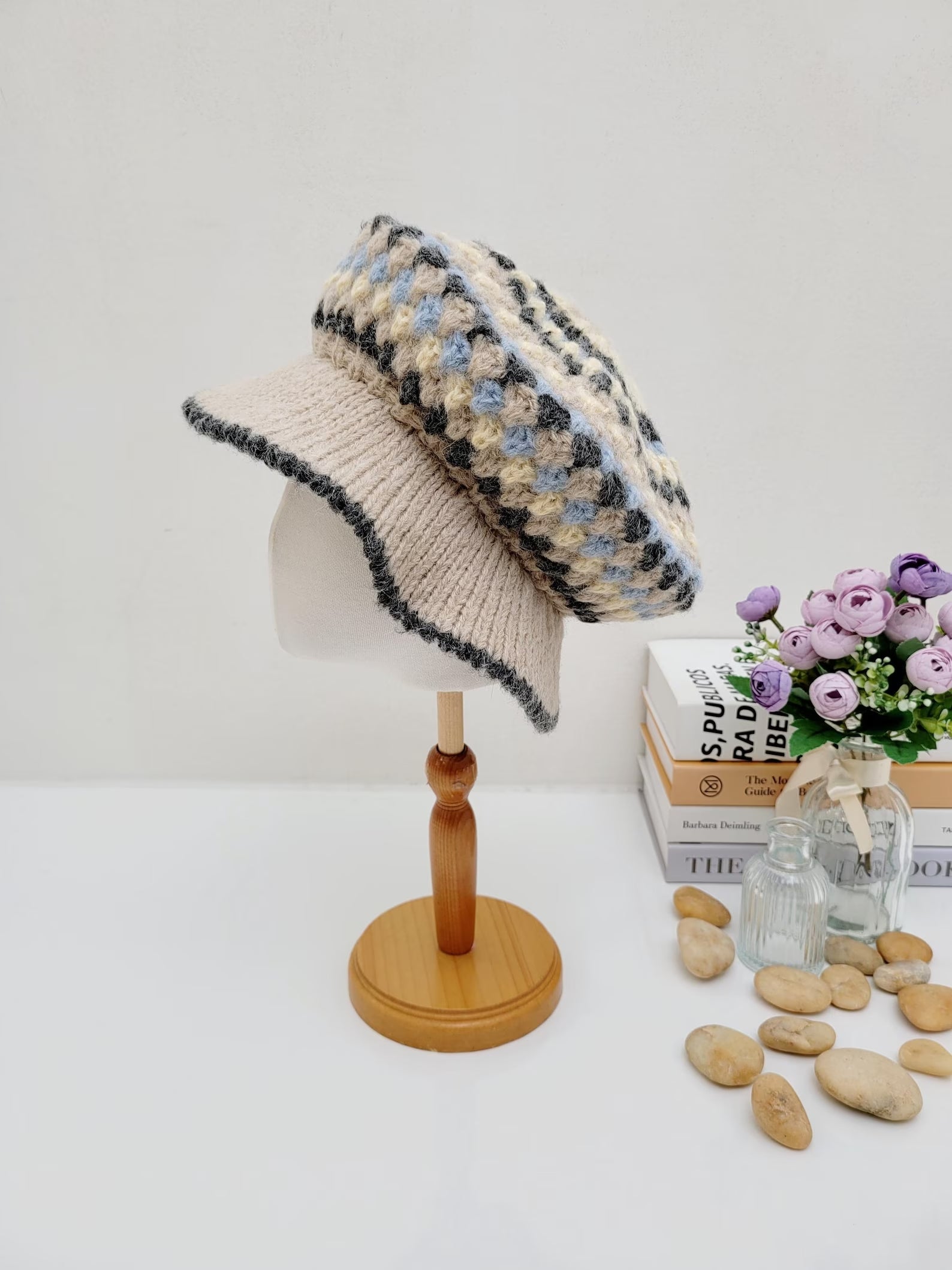 A collection of crocheted beret hats in various colors displayed on a wooden stand and table.