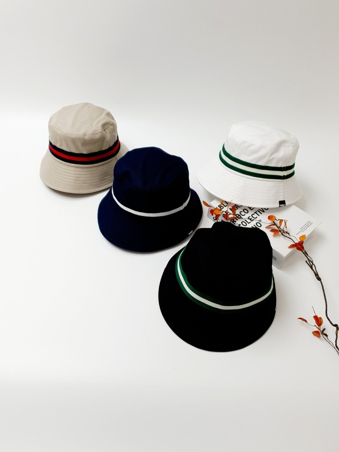 DAYTONA bucket hats: beige, navy, white, & black cotton hats, each with a sporty stripe accent. Stylish sun protection.