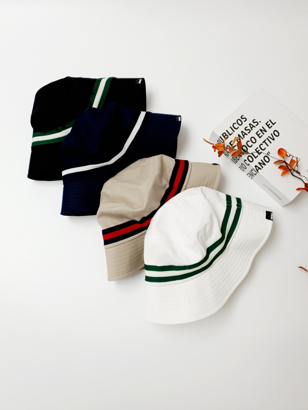 DAYTONA bucket hats: black, navy, beige, and white cotton hats, each featuring a sporty contrasting stripe detail.