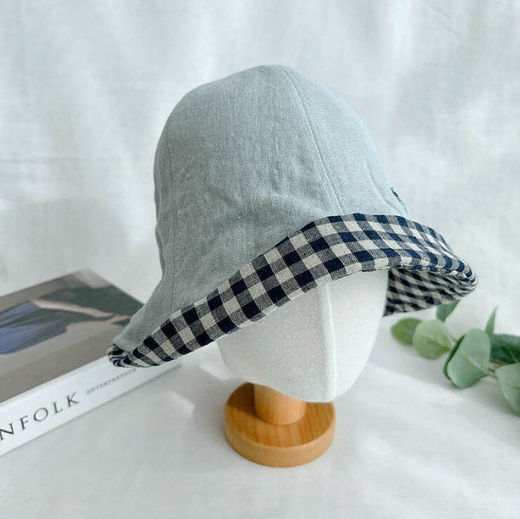 Linen checkered bucket hat with a light blue crown and navy-and-beige gingham brim, displayed on a mannequin head.