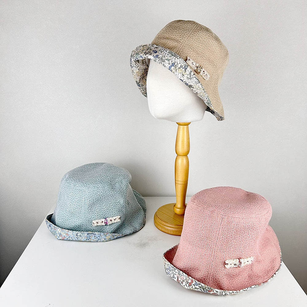 cotton viscose summer bucket hats in beige, blue, and pink. Each hat features a floral trim and a small bow detail, perfect for summer.