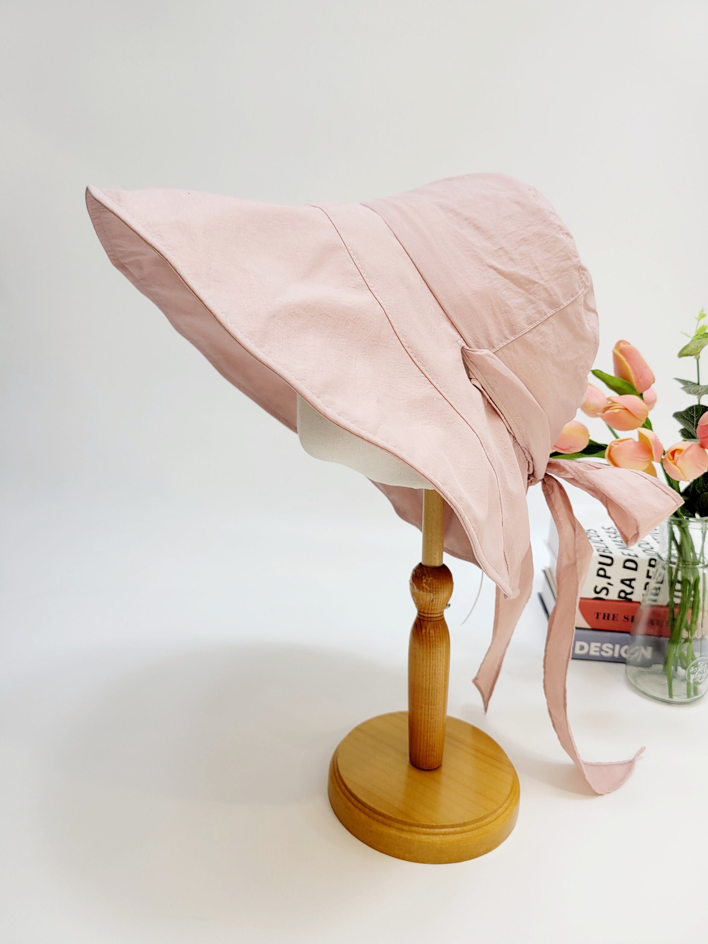 Pink "my fair lady" sun hat on a stand, featuring a wide brim and tied bow, perfect for sun protection