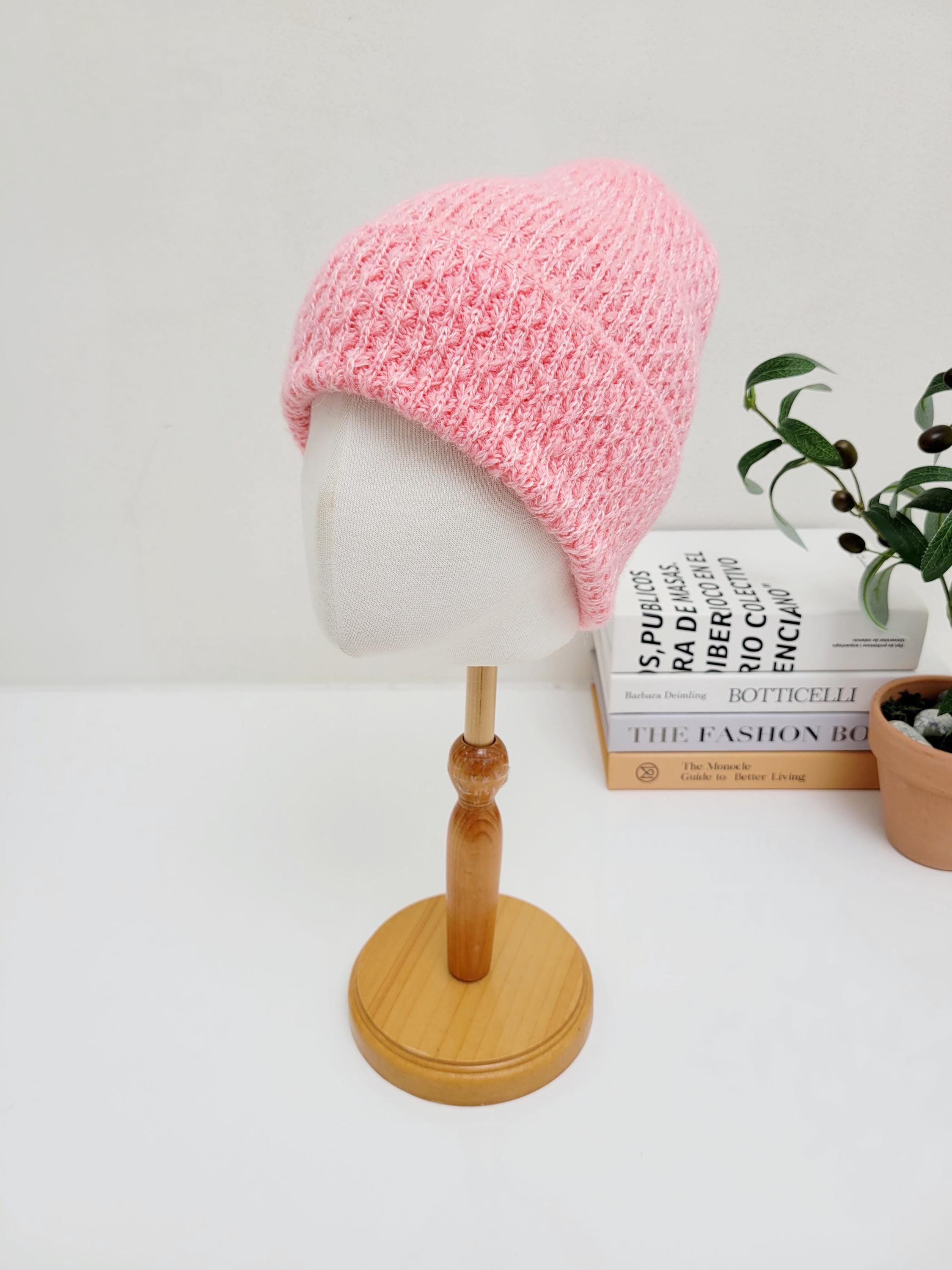 Soft pink knit TAYLOR beanie on wooden stand. A warm and stylish winter hat.