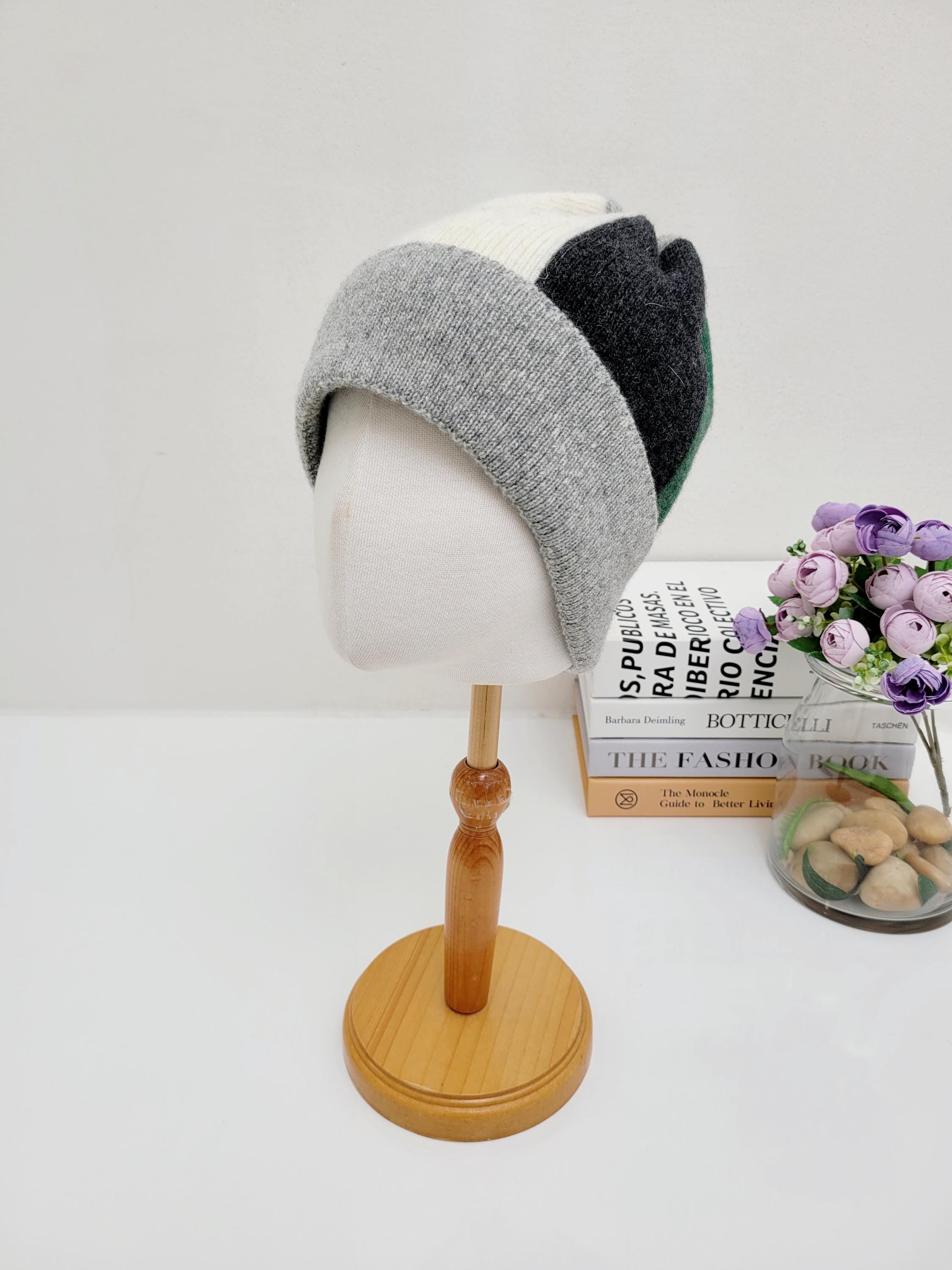 color block wool beanie: Stylish gray, white, dark gray, and green beanie displayed on a mannequin head.