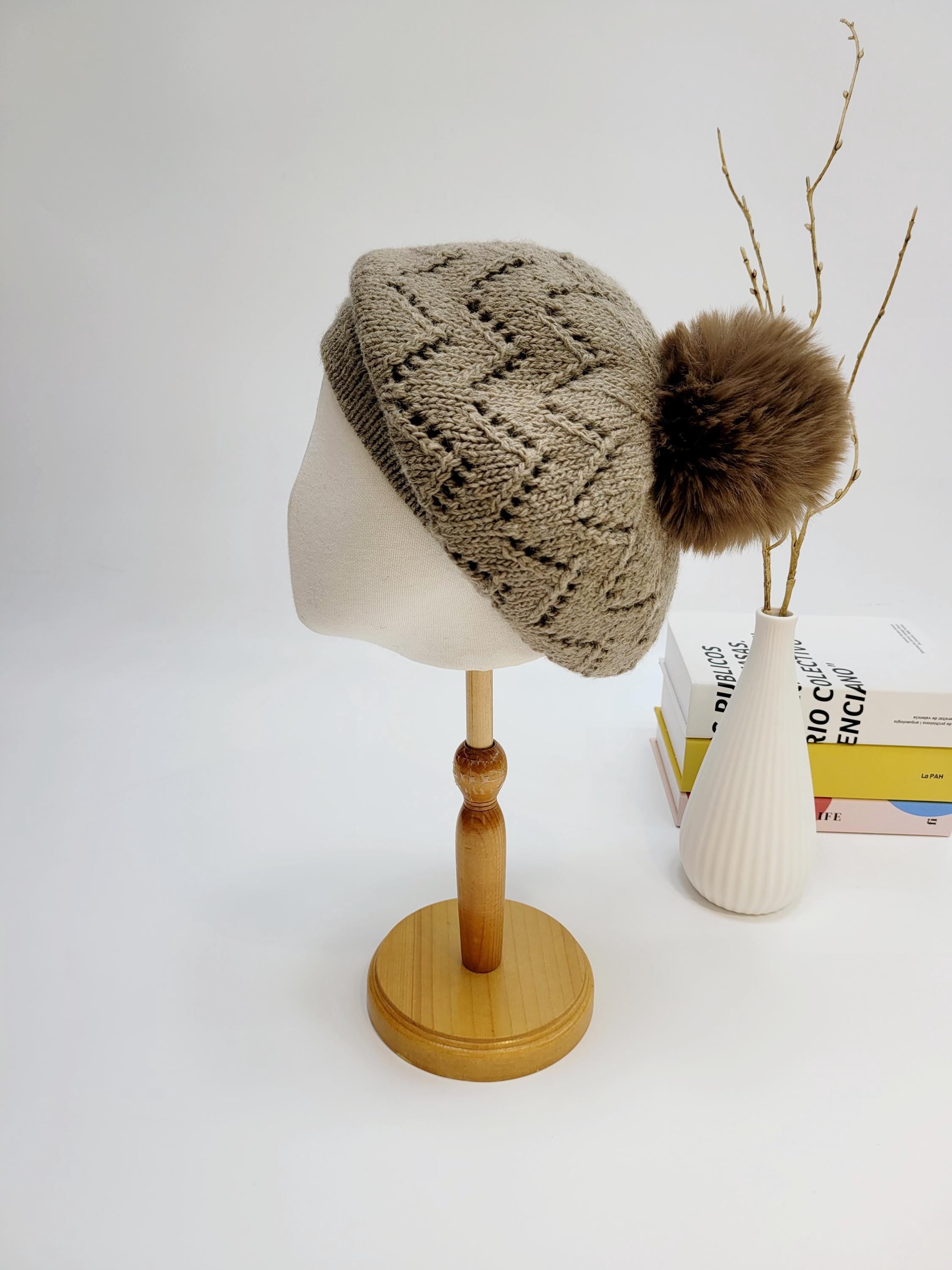 emma in paris beige knit beret with a geometric pattern and a fluffy brown faux fur pompom, displayed on a mannequin head.