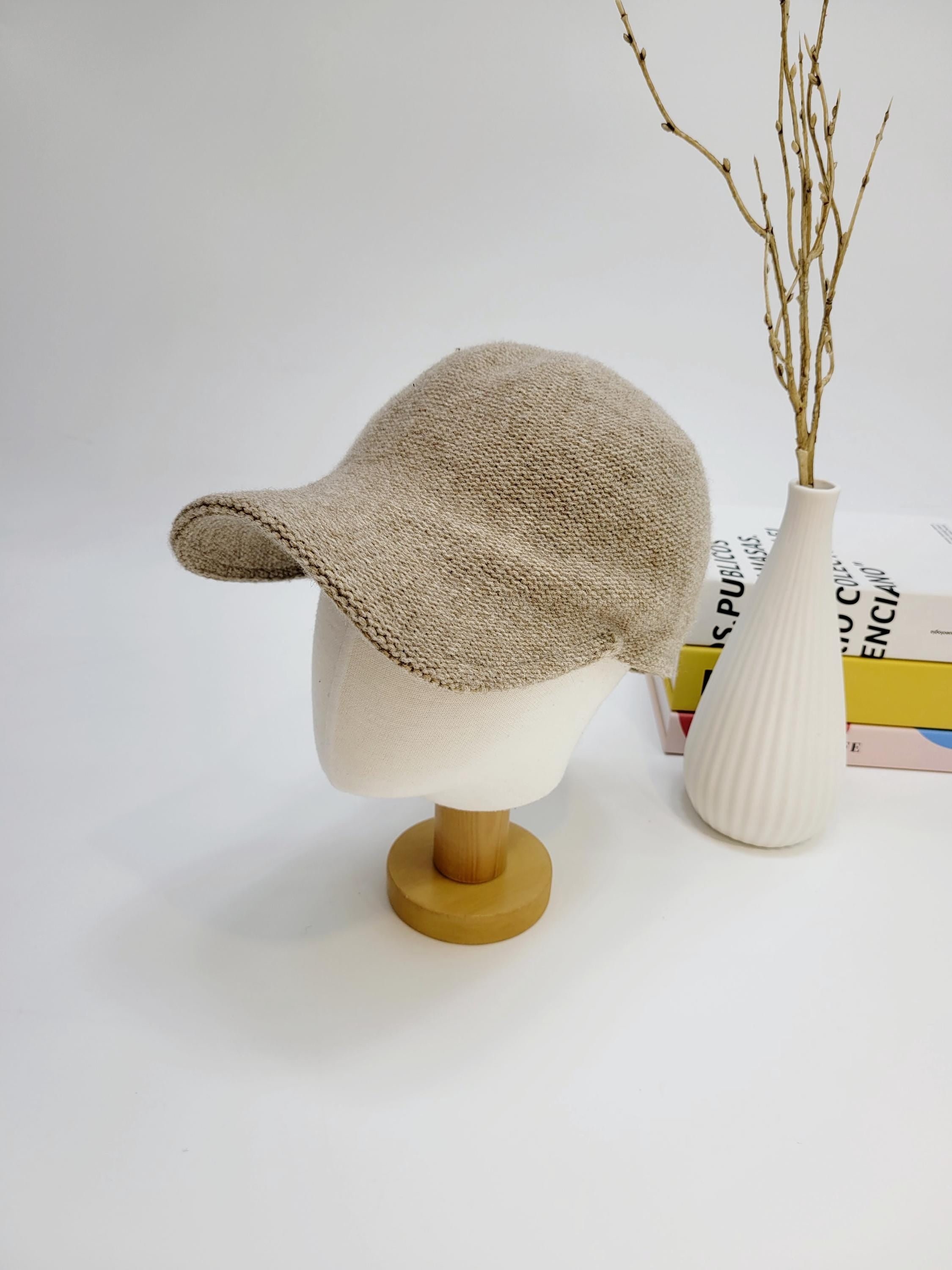 Beige wool cap on a mannequin head. Knitted texture, short brim, casual style.