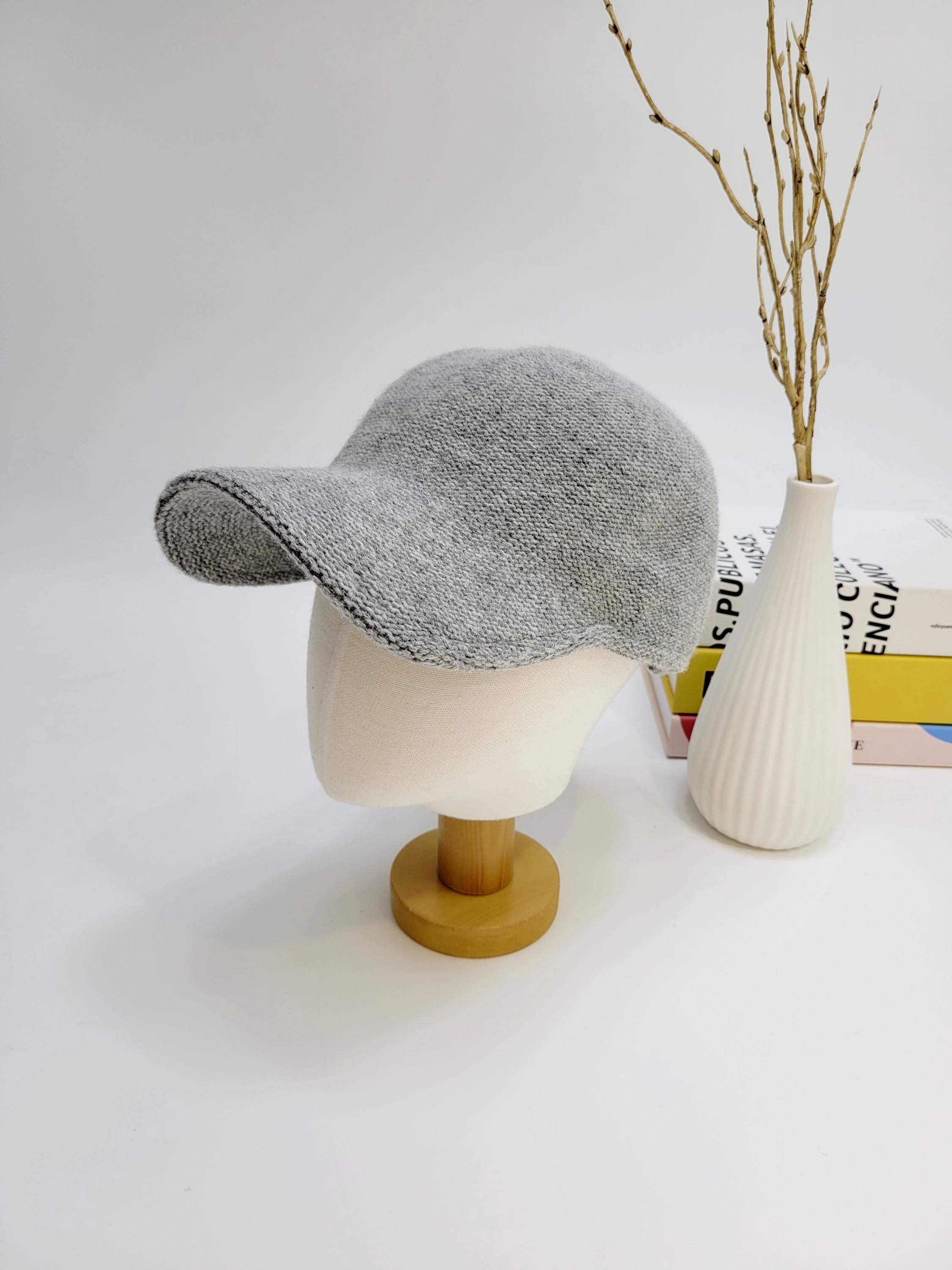 Grey knitted wool cap on mannequin. Classic baseball cap style, soft texture, perfect for casual wear.