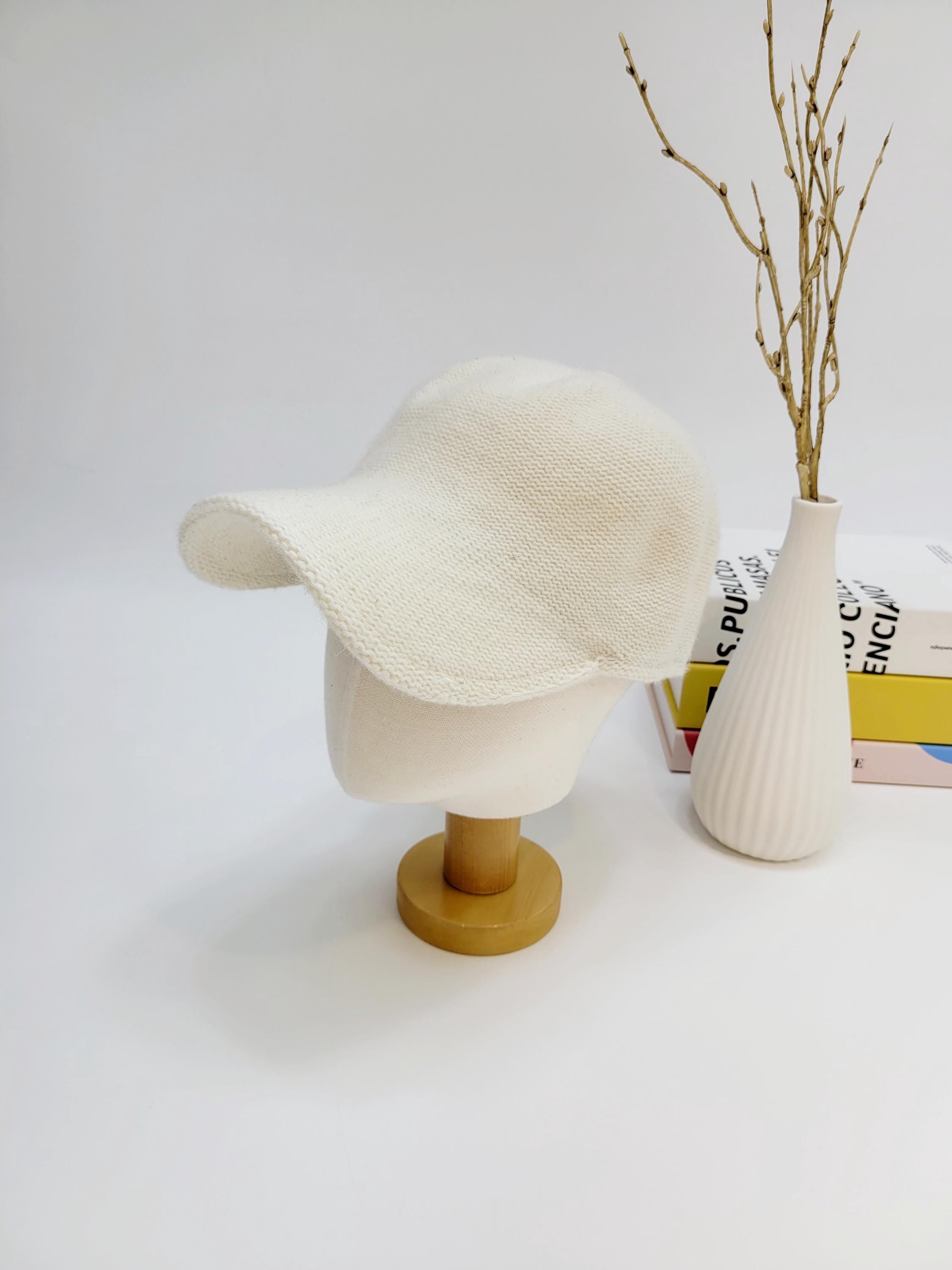 Cream wool cap on a mannequin head, featuring a soft, knitted texture and a curved brim.