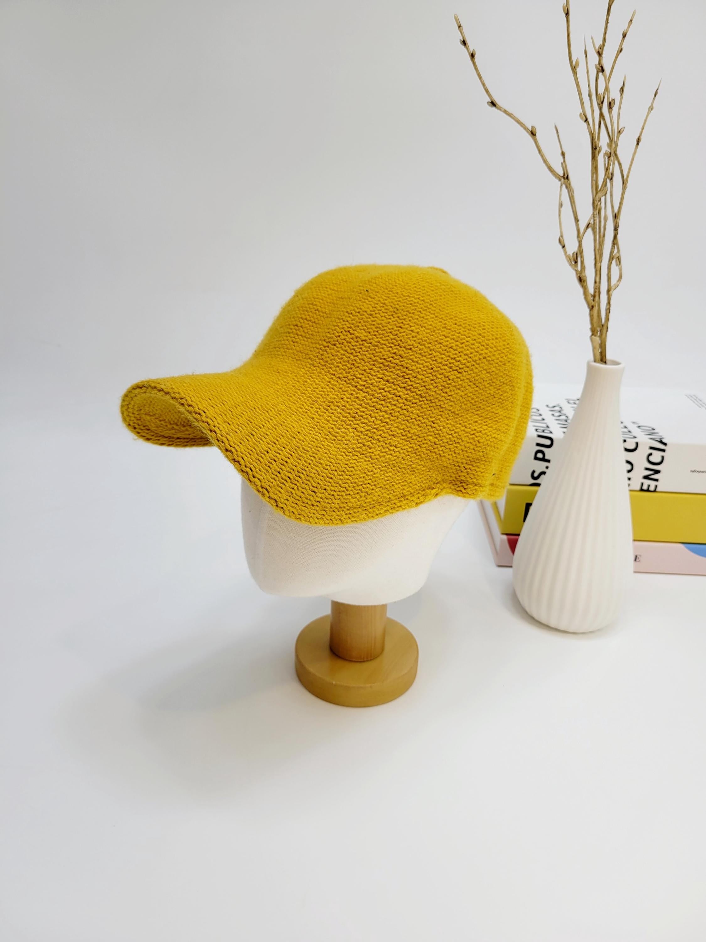 Mustard yellow wool cap on a mannequin. A stylish and warm knitted hat.