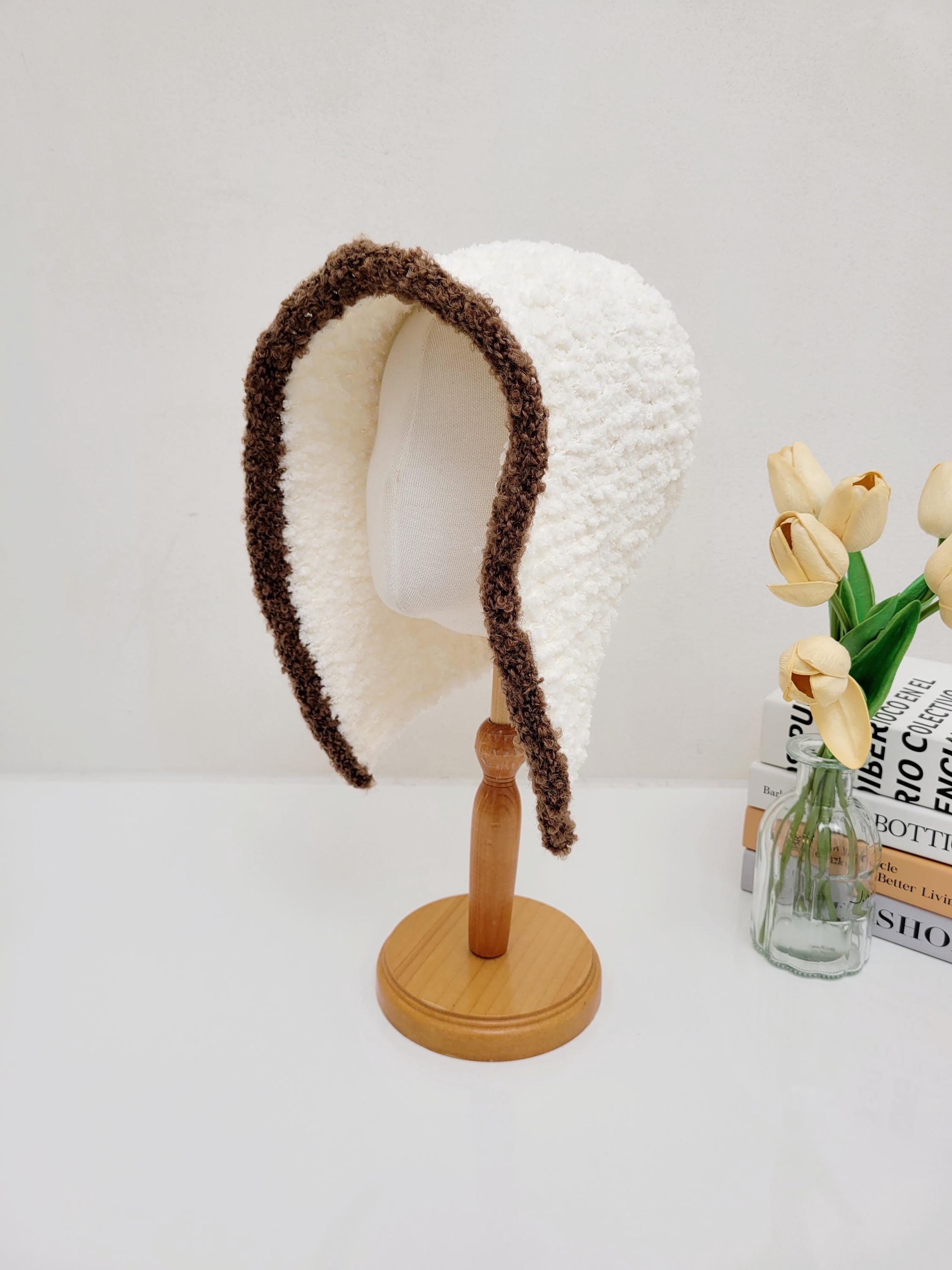 Creamy white wool hooded hat with a brown trim, shown on a mannequin head.