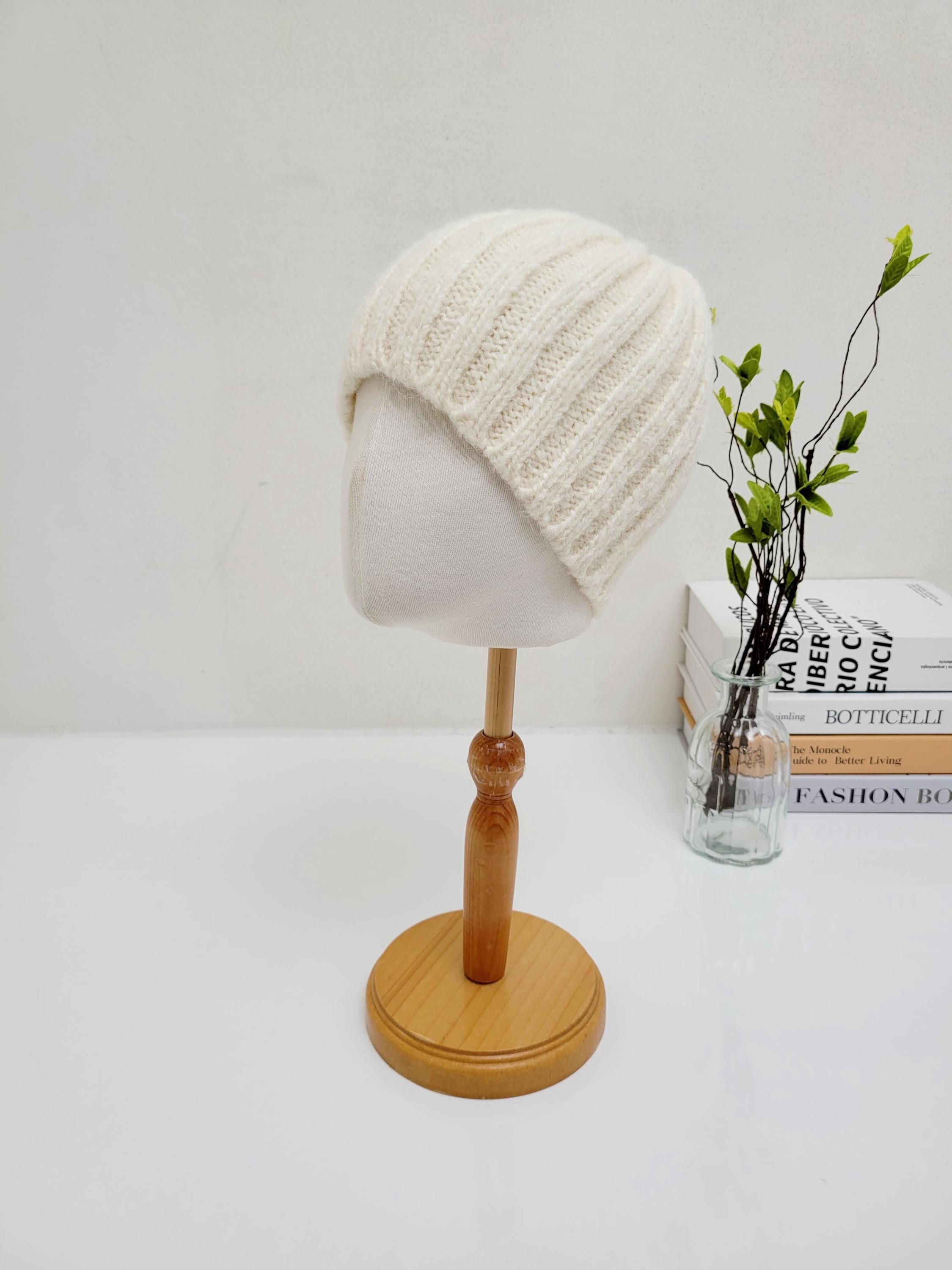 Cream-colored WIDE RIB WOOL BEANIE. Soft, ribbed knit on a mannequin head. A cozy and stylish winter accessory.