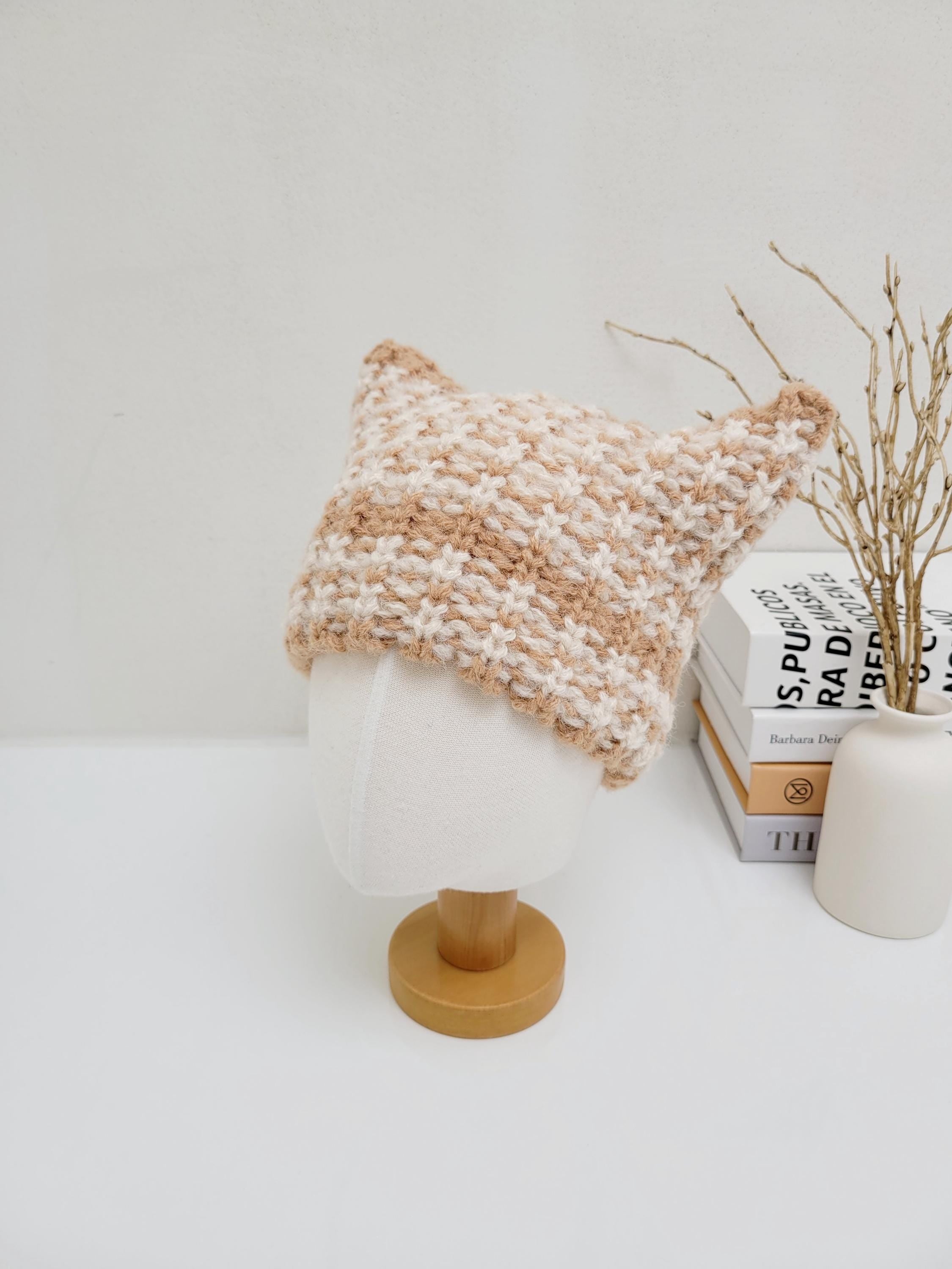 Cream and tan knitted cat ear hat on a mannequin head. Cozy and cute.