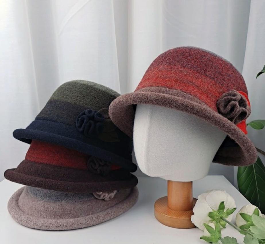 Stacked felt kelly hats in various ombre colors, each with a flower detail. One red ombre hat is displayed on a mannequin head.
