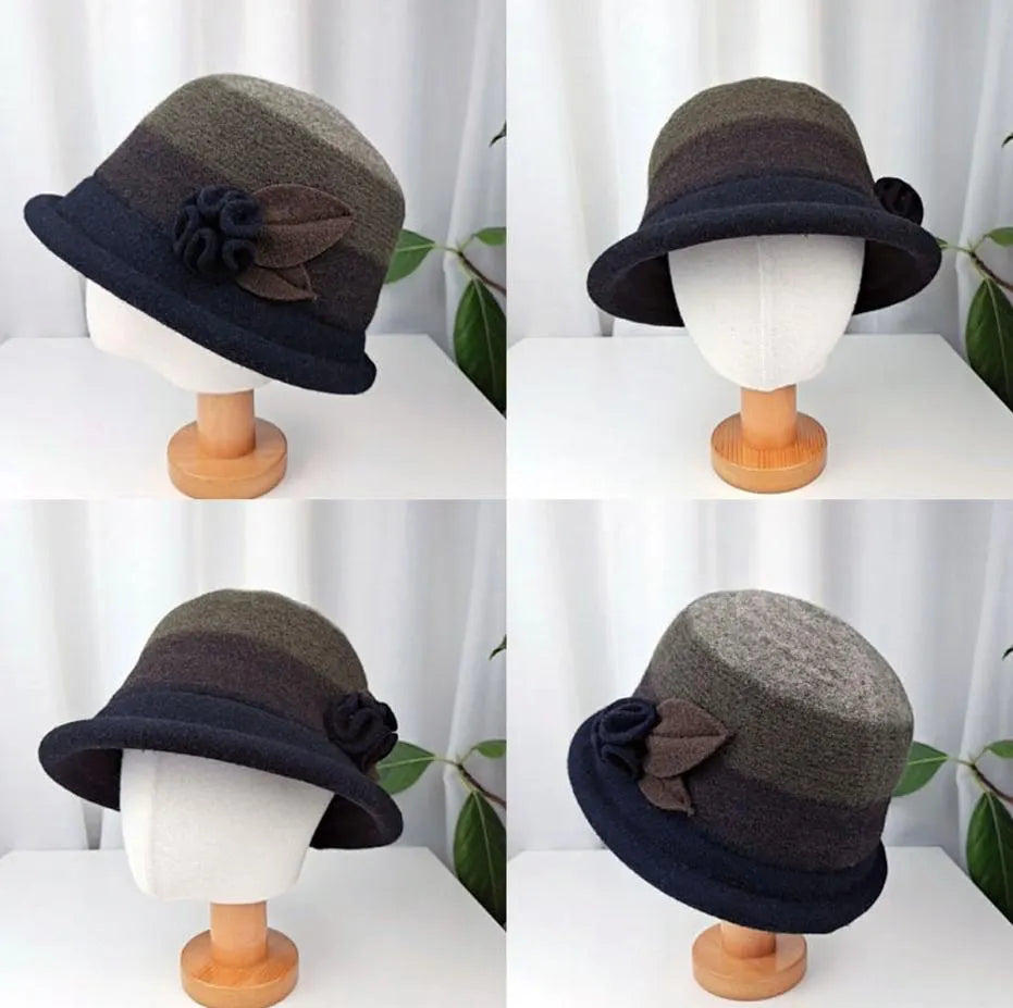 kelly hat: Dark blue & gradient brown/green cloche hat with fabric flower detail, displayed on a wooden stand.