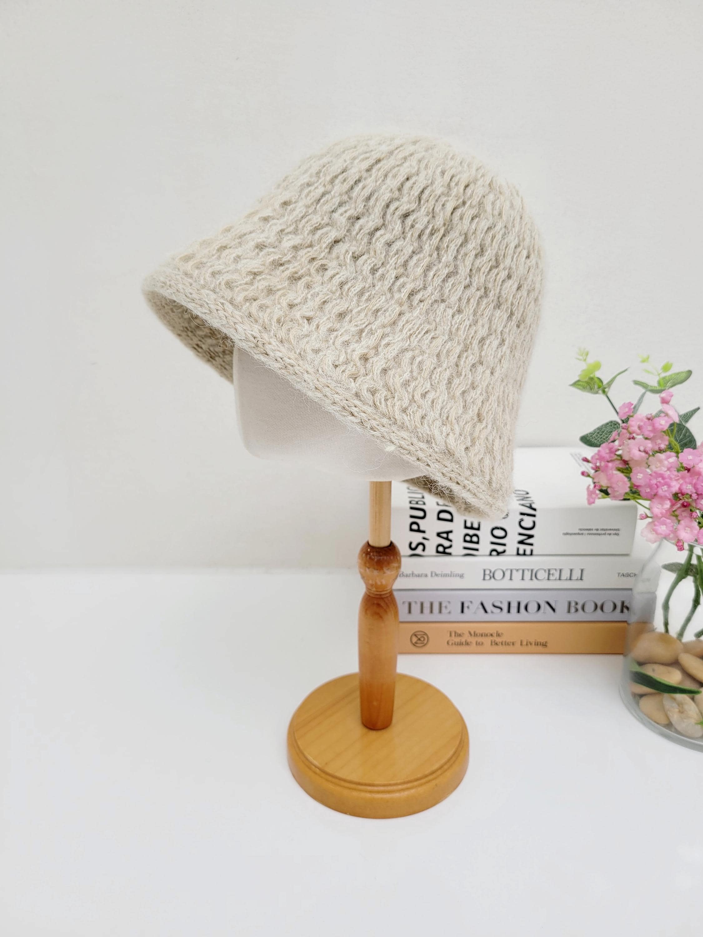 Beige wool bucket hat with a textured knit pattern, displayed on a mannequin head on a wooden stand