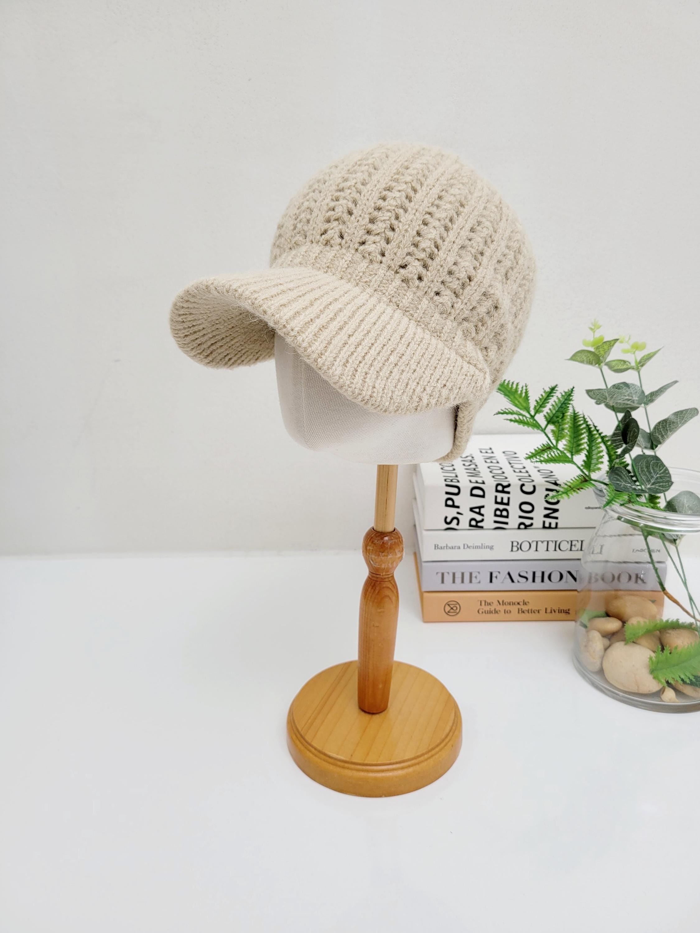 
<output>Beige crochet baseball cap on a wooden stand. A stylish, textured knit hat with a curved brim, perfect for casual wear.