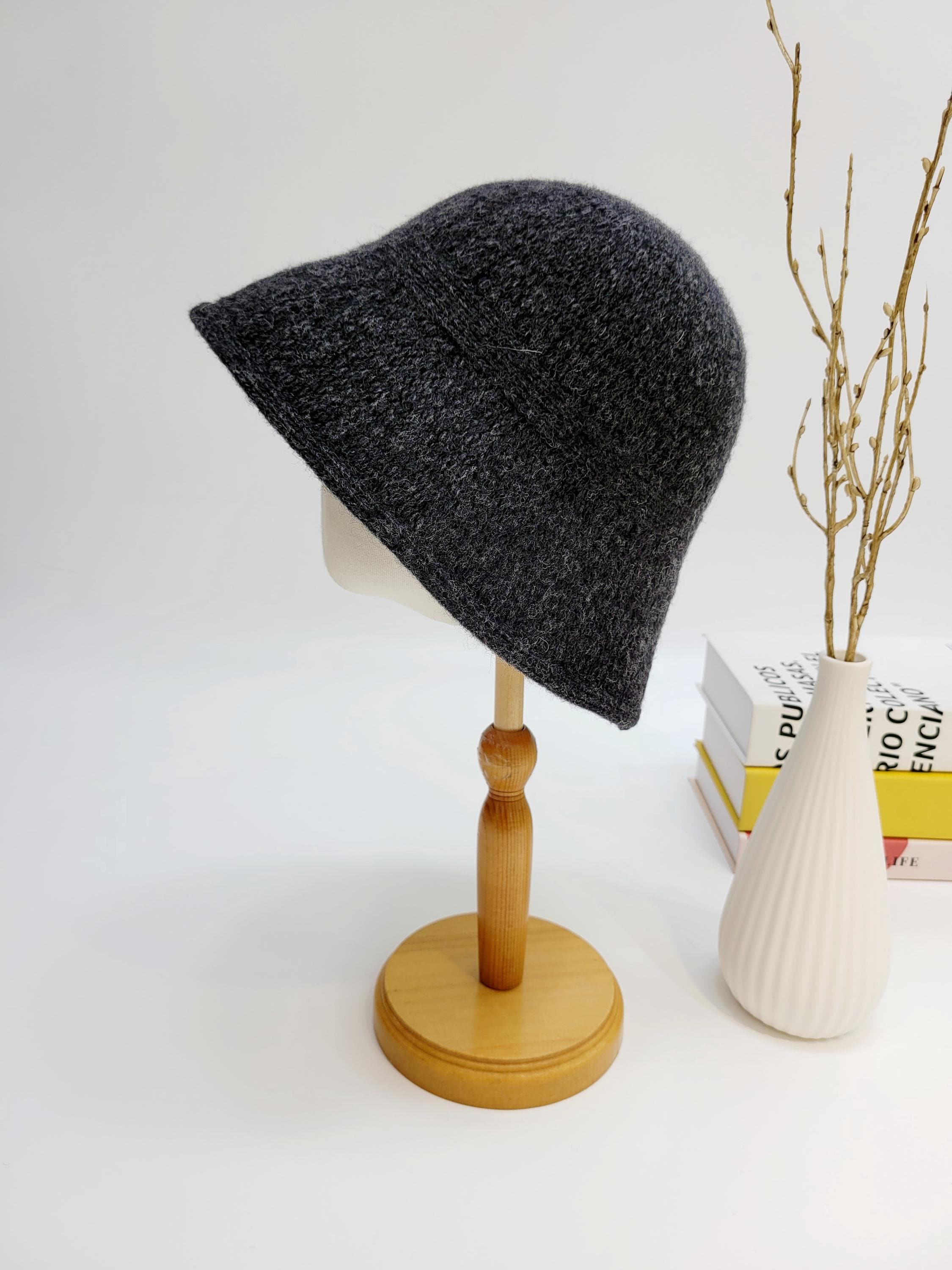 Dark gray felt victoria's winter hat on a wooden stand. A soft, stylish bucket hat for cold weather.