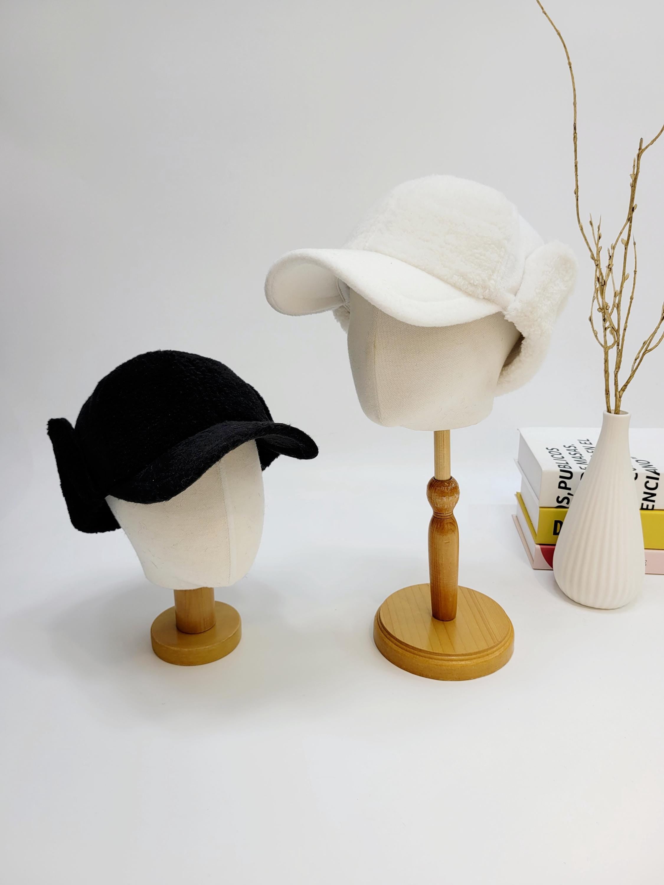Black and white winter hats from jennifer on the street, each displayed on a mannequin head, showcasing their soft, plush textures and ear covering flaps.