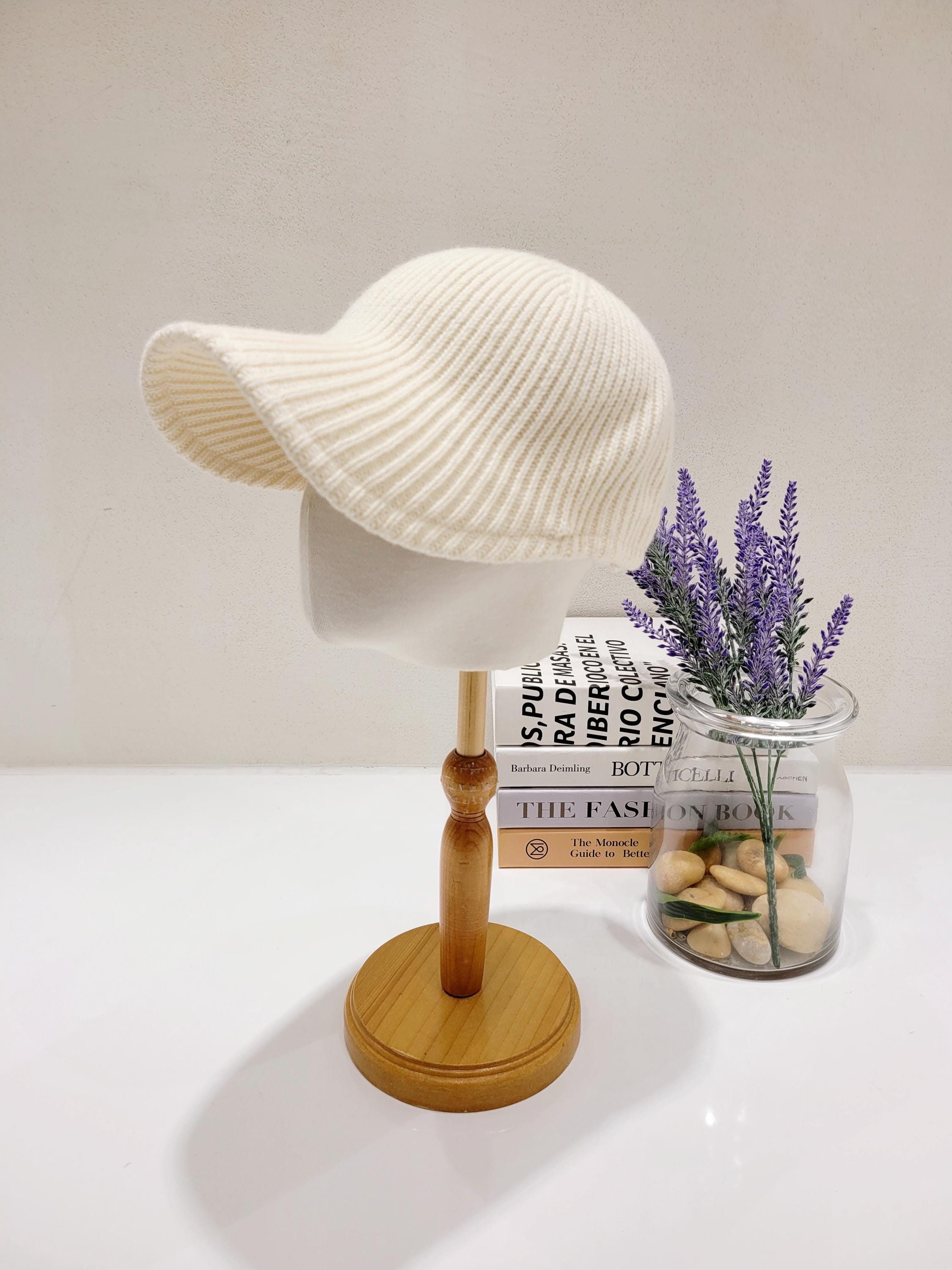 Creamy white wool ribbed cap displayed on a mannequin head, featuring a subtle brim and soft, textured knit.