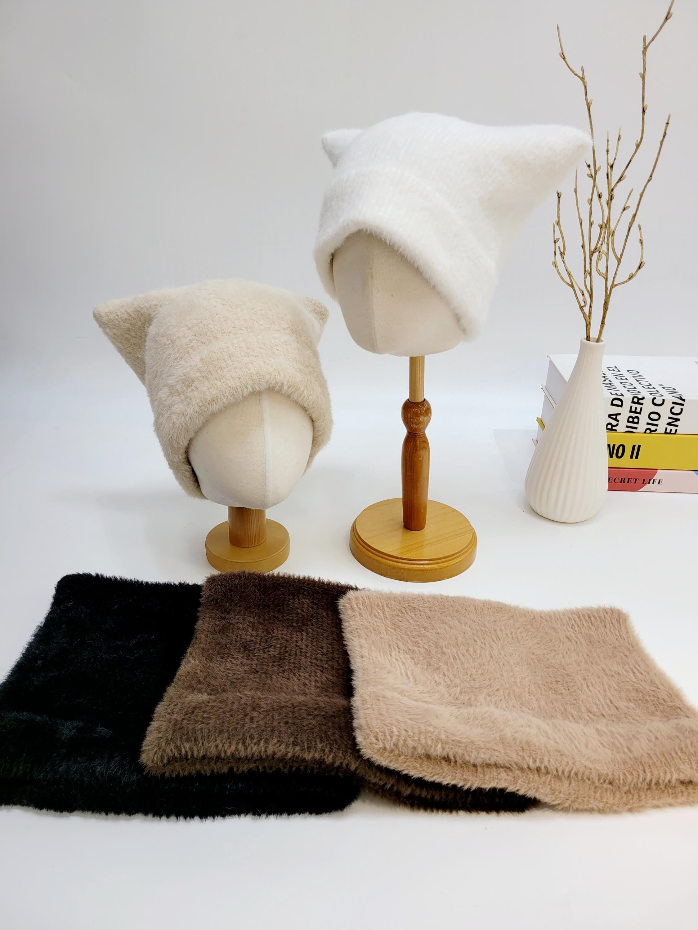 ELF IN THE HAT: White and beige fluffy cat ear beanies on mannequin heads, with matching winter scarves in black, brown, and beige.