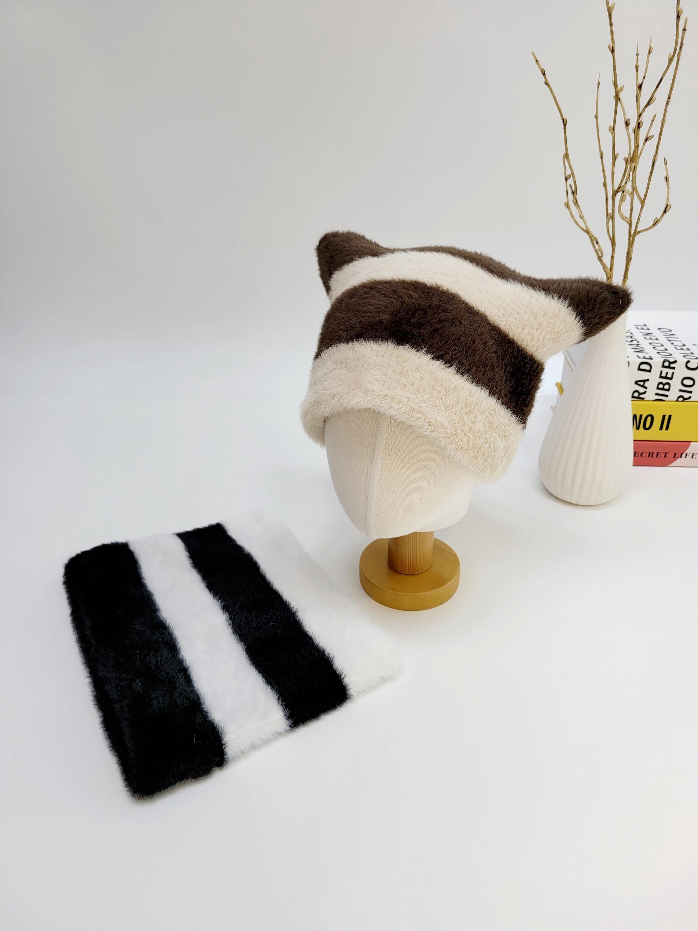 Brown and cream striped cat ear-stripe hat with matching scarf. Soft, plush texture; whimsical design on a white surface.