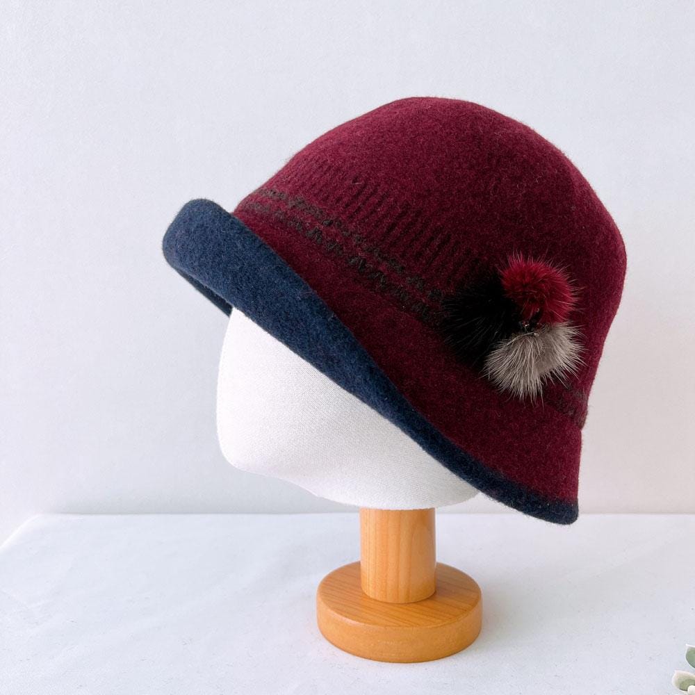Burgundy my first lady hat - wool with navy brim and cute pompom detail, displayed on a mannequin head