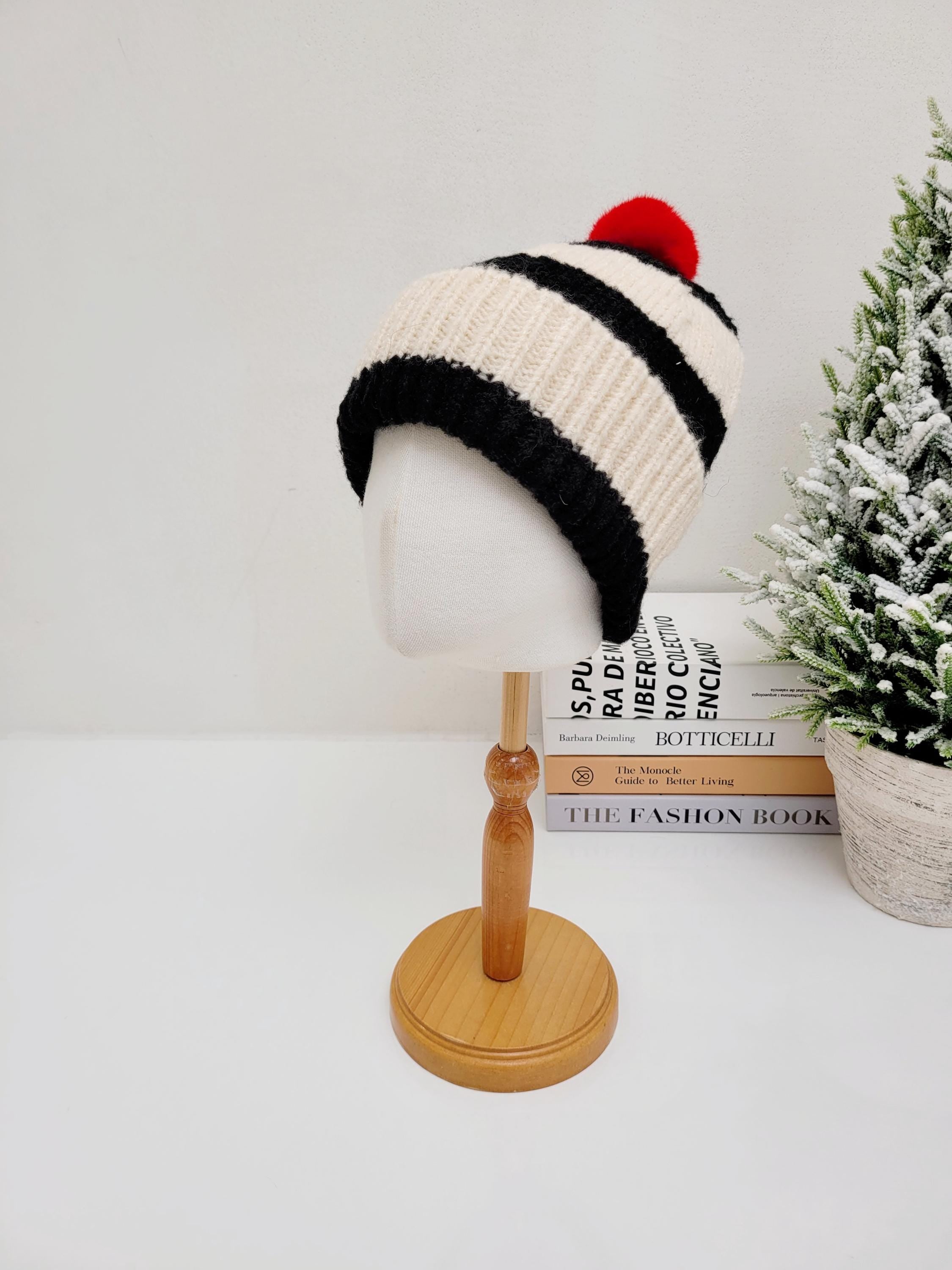 paris - b&w beanie: Cream and black striped knit hat with a vibrant red pom-pom on a mannequin head.