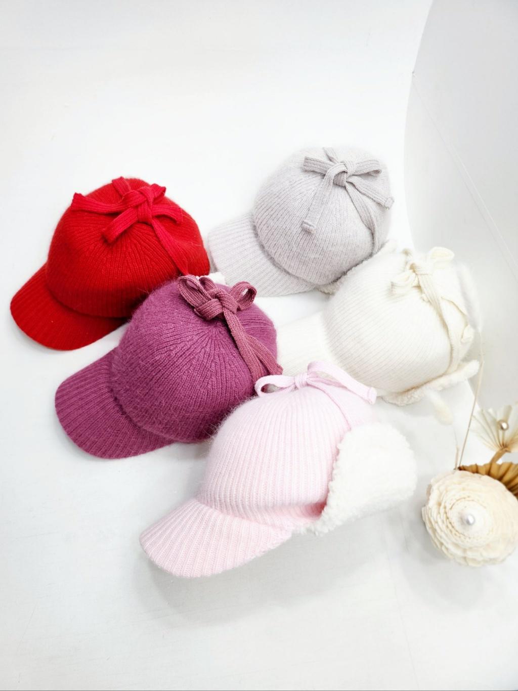 Angora trapper earflap hats in red, purple, gray, white, and pink. Each knitted cap features a charming bow detail.