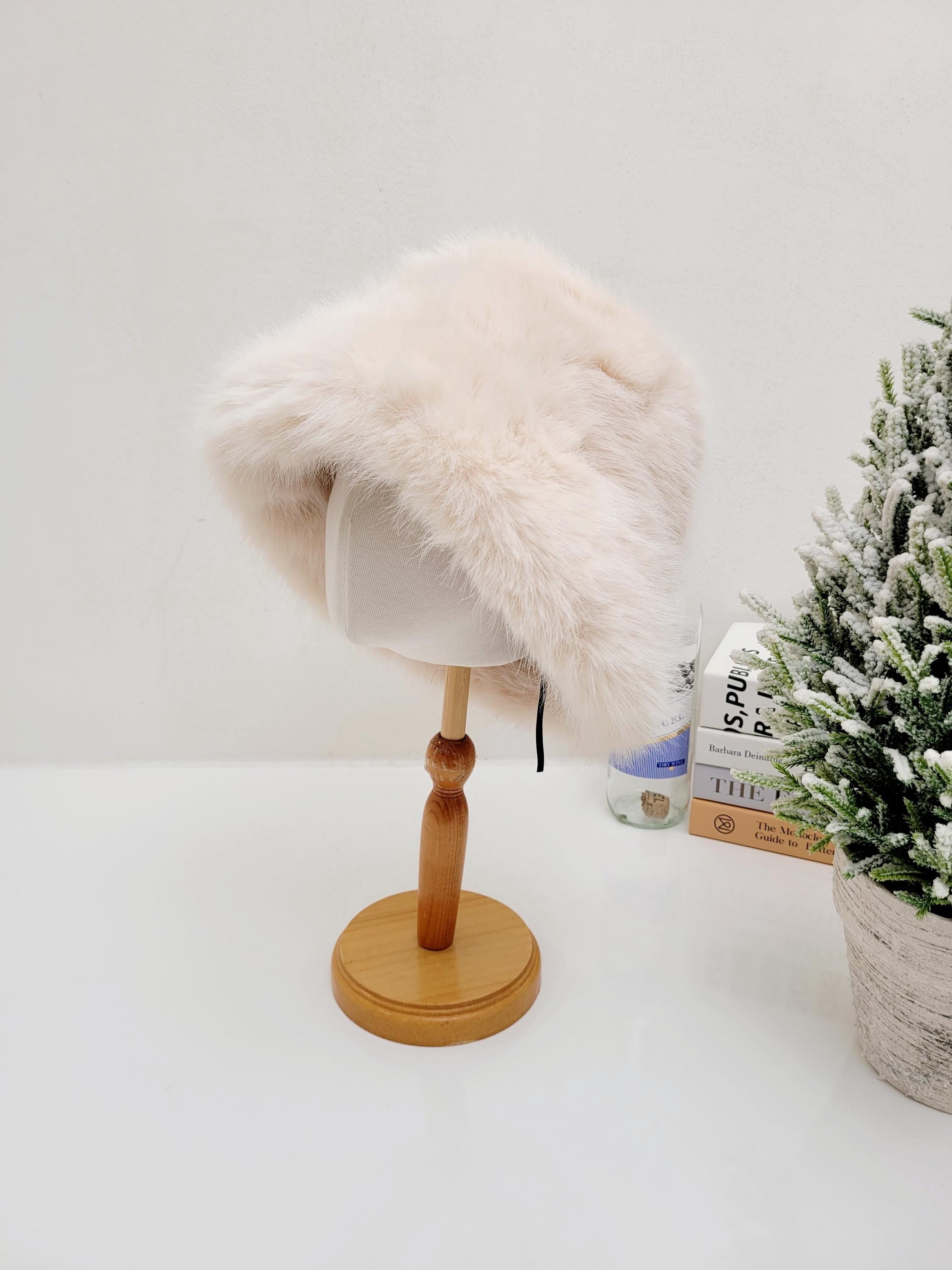 Light pink fake fur angelina winter spy hat on a wooden display stand. Soft and fuzzy texture, perfect for winter.